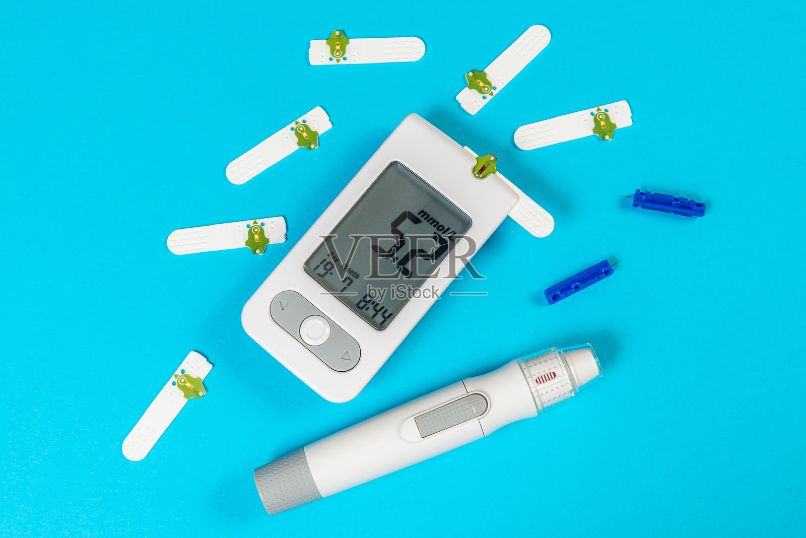 蓝色背景上的血糖仪和胰岛素笔,整齐排列的试纸和采血针。照片摄影图片
