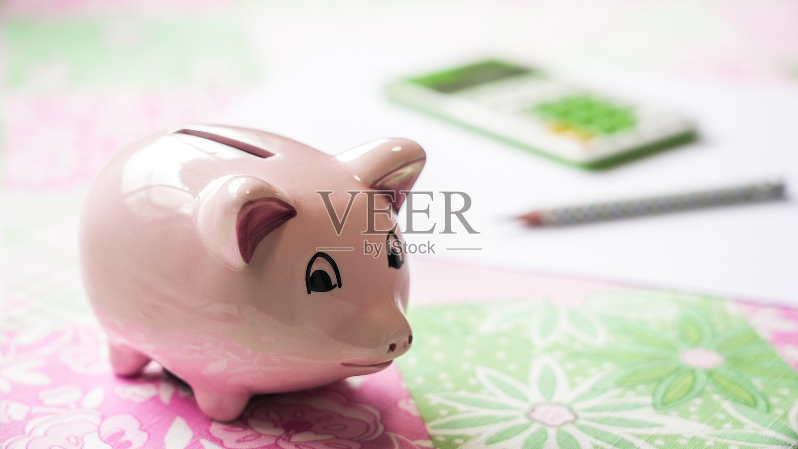 桌子上的储蓄罐,后面有计算器和铅笔照片摄影图片