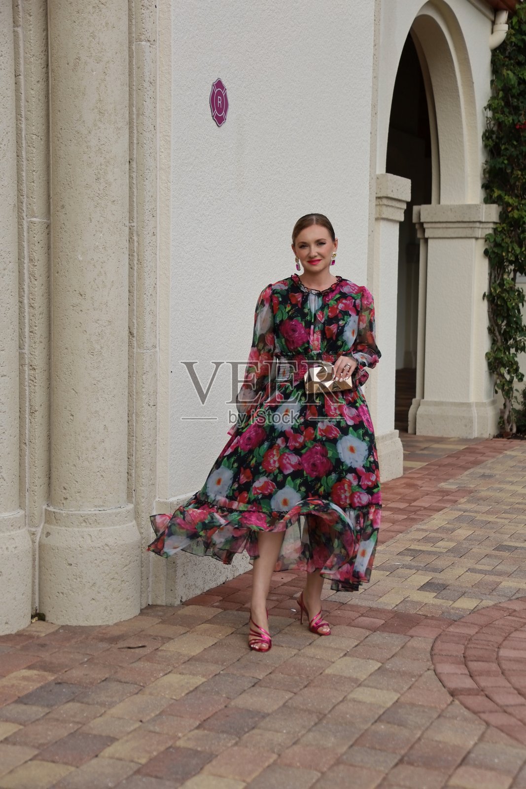 年轻美丽的女性穿着印花长裙,手提金色手袋照片摄影图片