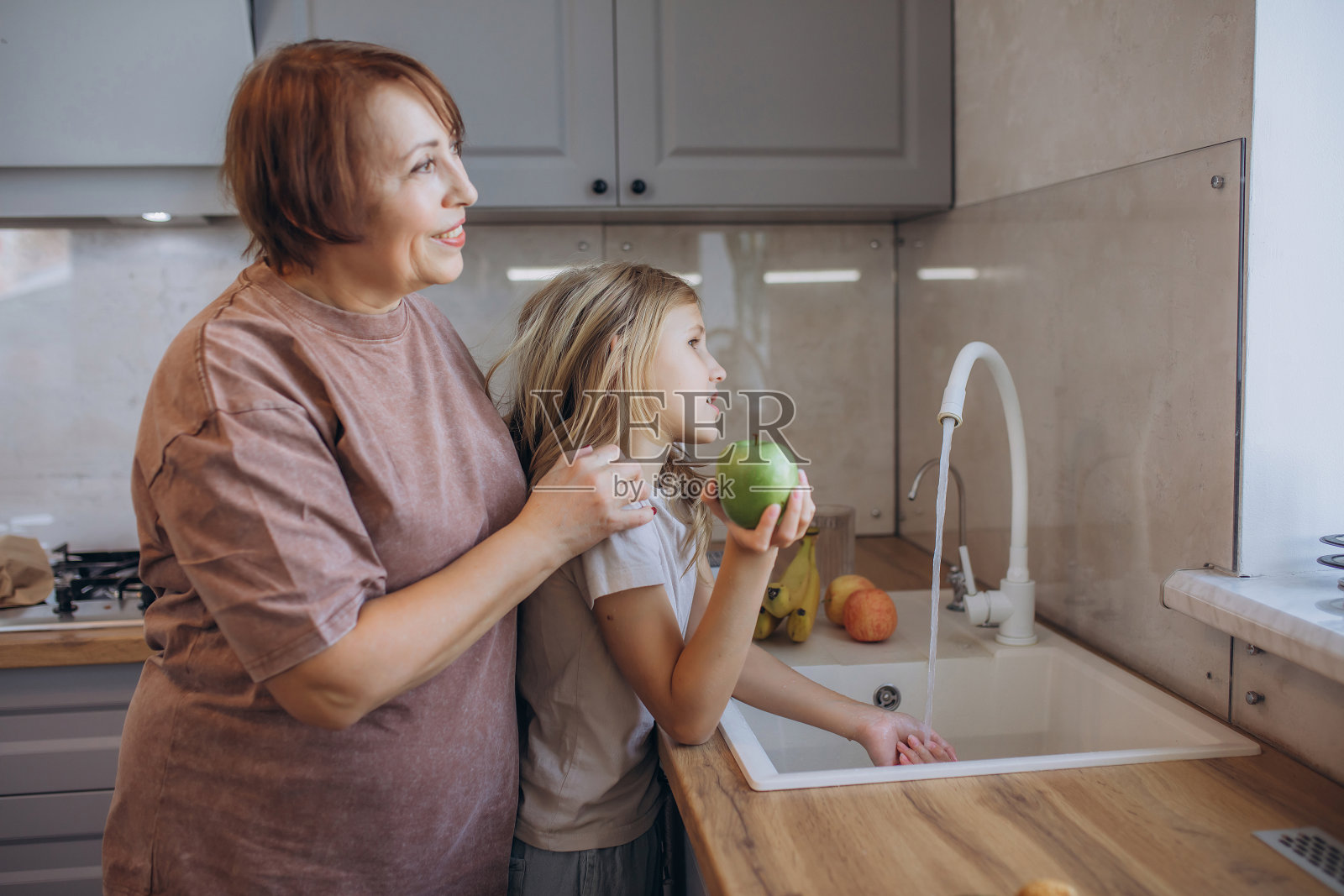 祖母和孙女一起洗苹果,学习厨房卫生知识照片摄影图片