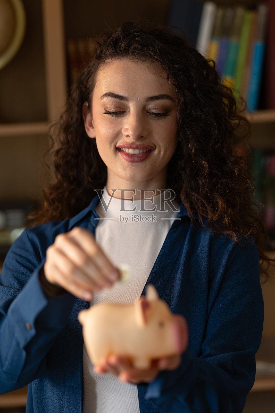 年轻女性将钱放入储蓄罐,管理个人财务并做出明智的财务决策照片摄影图片