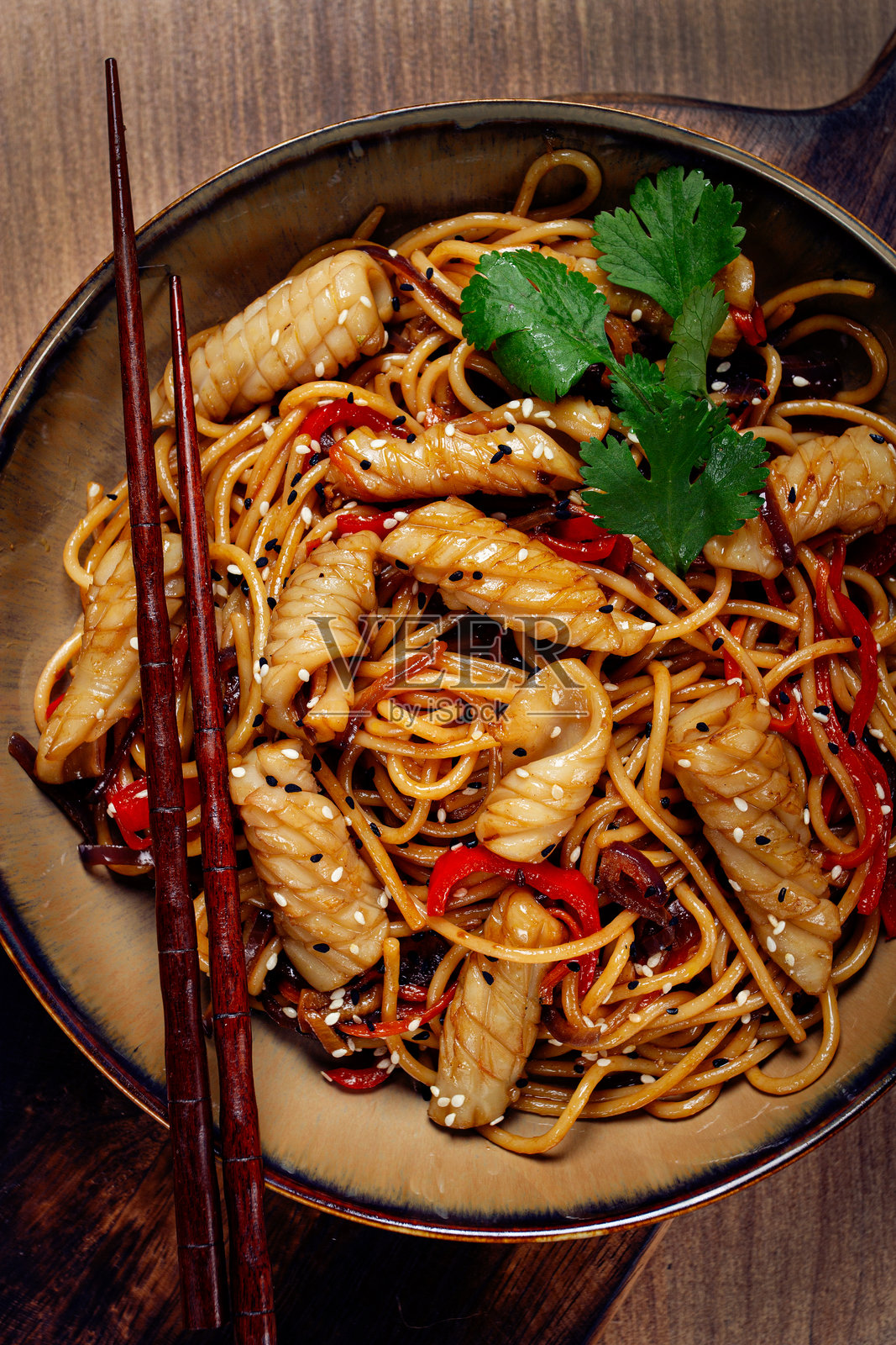 自制的乌冬面,配有鱿鱼和蔬菜,放在木桌上,无人。照片摄影图片