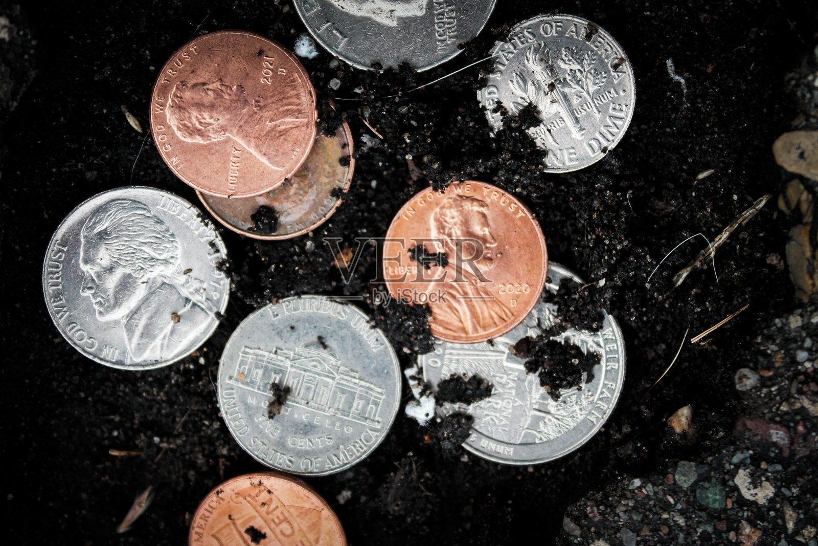 路面坑洞中的硬币,象征金钱的抽象背景照片摄影图片