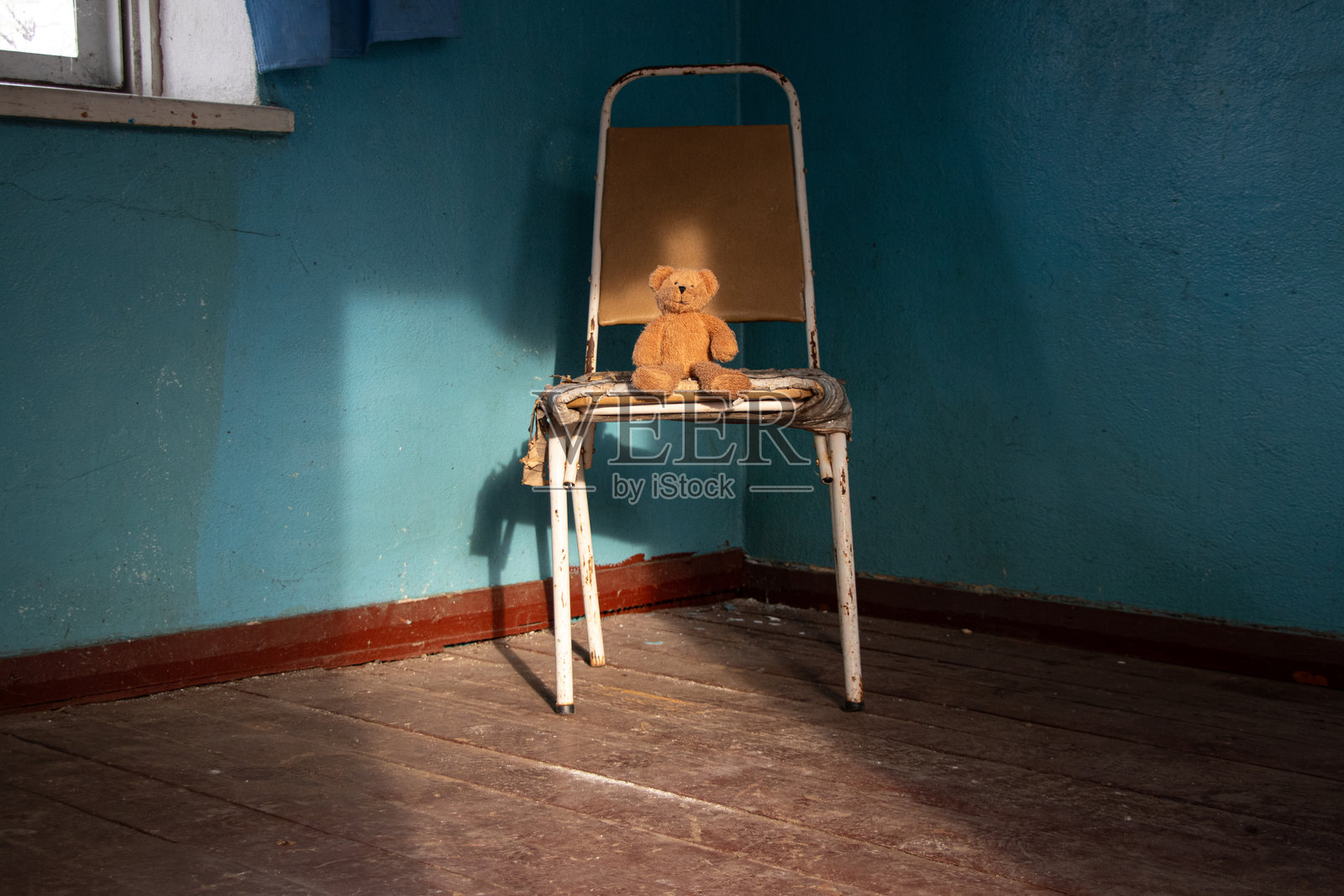 棕色柔软的泰迪熊坐在乌克兰一座被遗忘的旧废弃房子里的椅子上照片摄影图片