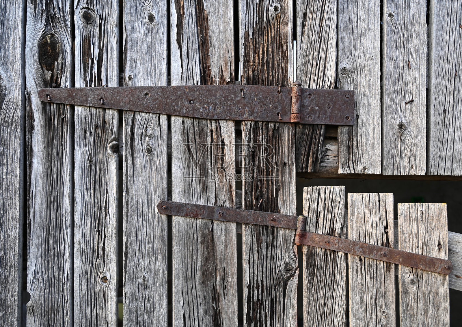 乡村环境中,带有金属铰链的乡村风格木门展现出风化的质感和历史魅力。照片摄影图片