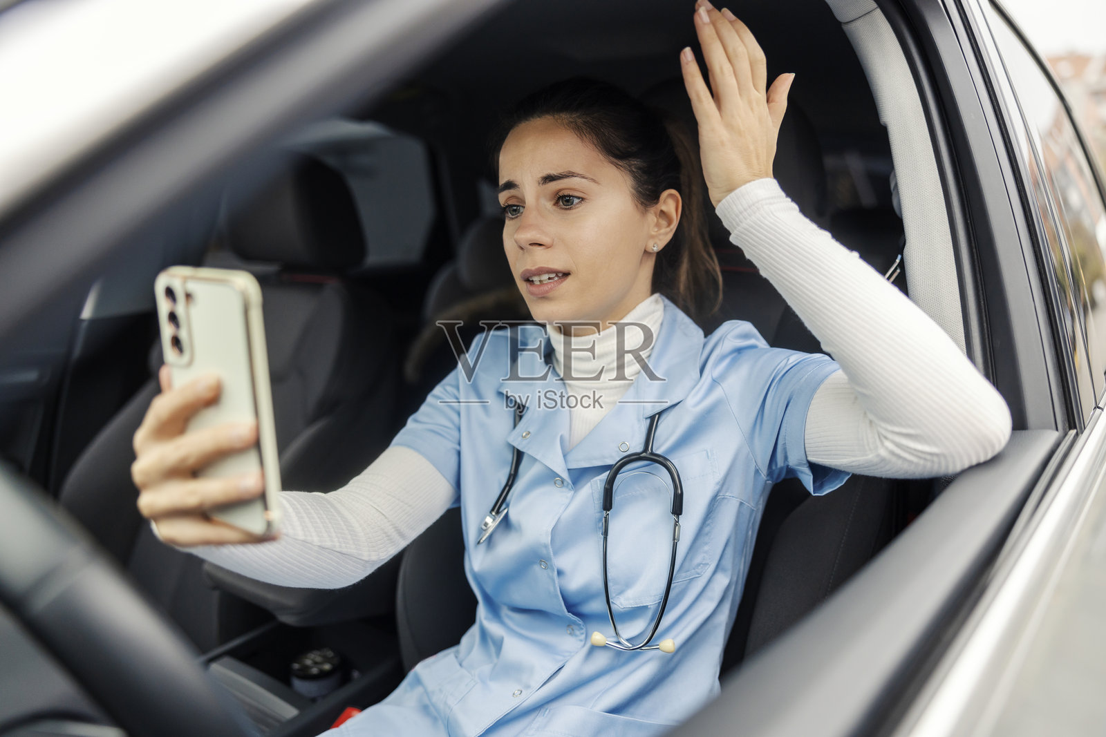 紧张的女医生坐在车里,通过电话进行在线会议争论。照片摄影图片
