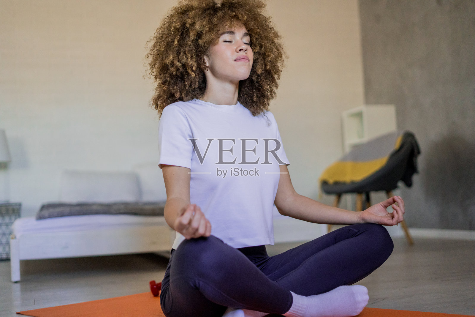 一位年轻女性在温暖舒适的客厅地板上练习瑜伽。放松的氛围、宁静以及对瑜伽的纯粹享受创造了一个完美的和平与和谐的时刻。照片摄影图片