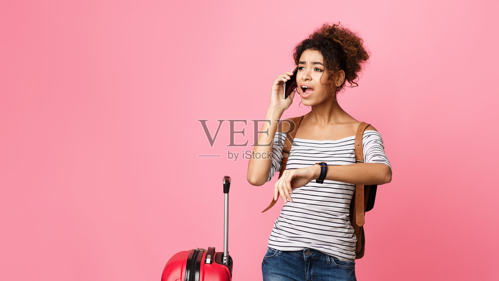 年轻旅行者在粉色背景前打电话时查看时间照片摄影图片