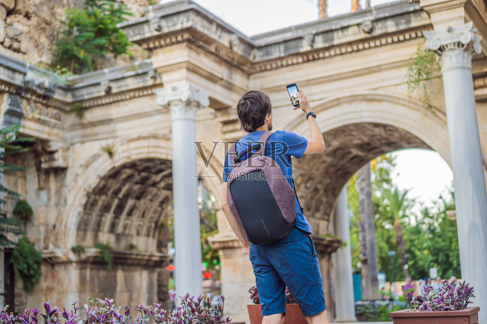 快乐的男性游客在安塔利亚老城发现有趣的地方和热门景点,游览哈德良门,土耳其的历史地标。受欢迎的旅游景点 - 安塔利亚老城的古罗马哈德良门。照片摄影图片