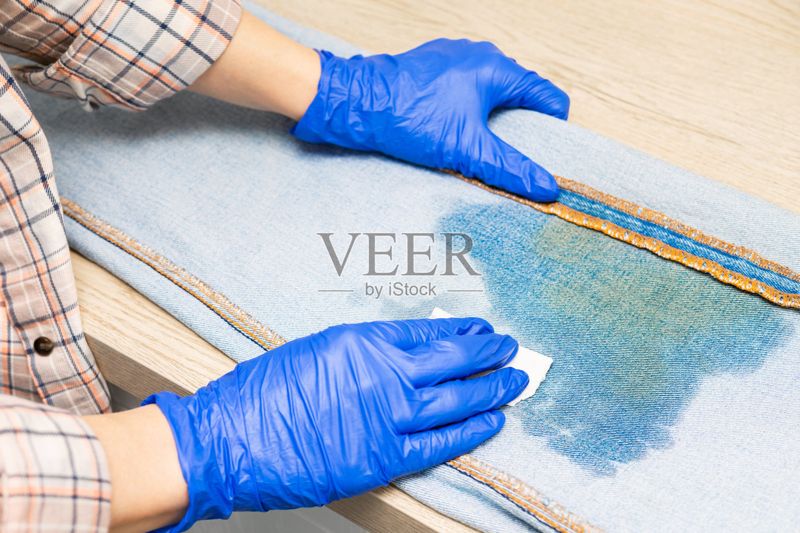 女人在近距离清除牛仔裤上的污渍。照片摄影图片