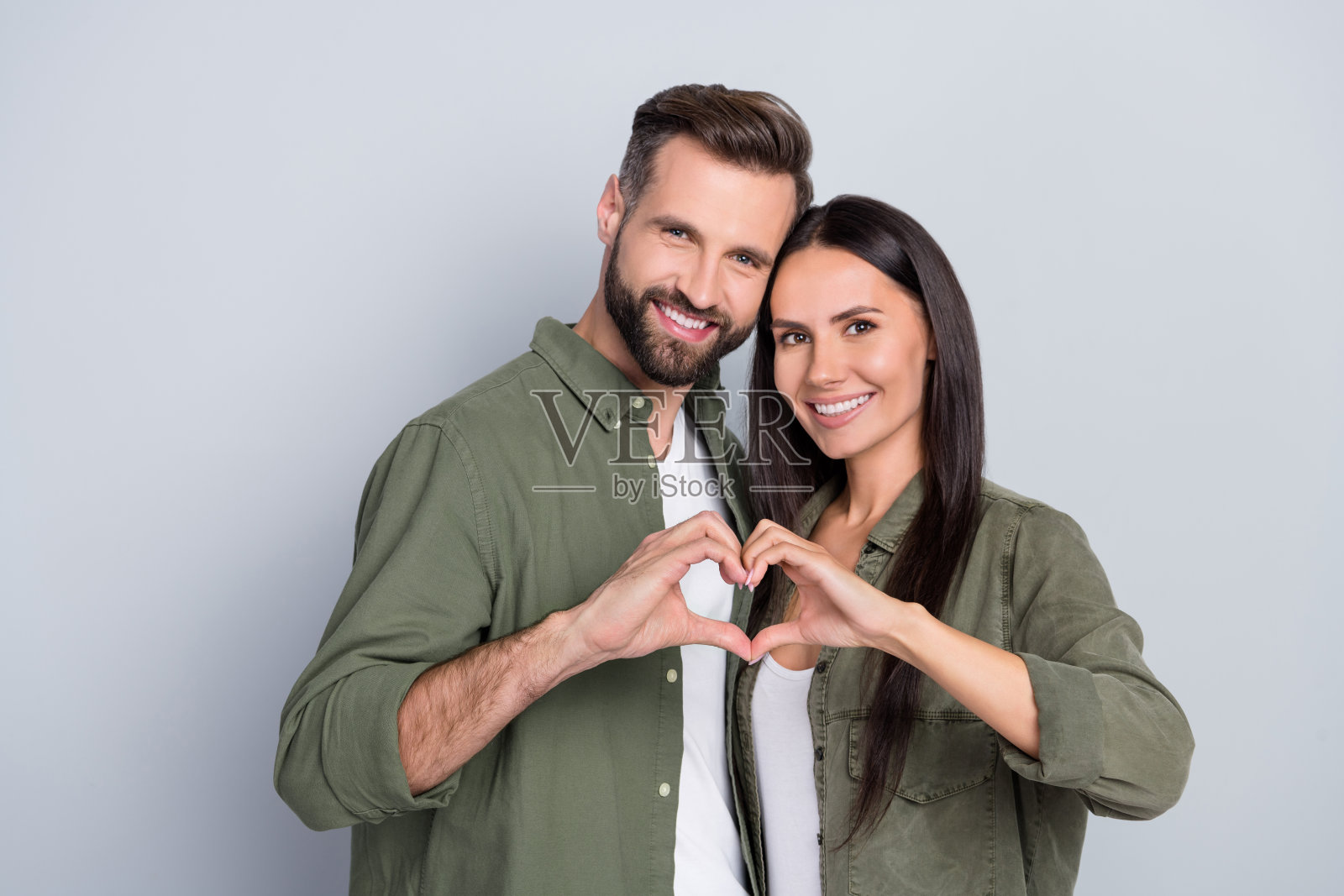 一对迷人快乐的情侣相拥,展示心形符号,爱神丘比特,背景为灰色柔和色调。照片摄影图片