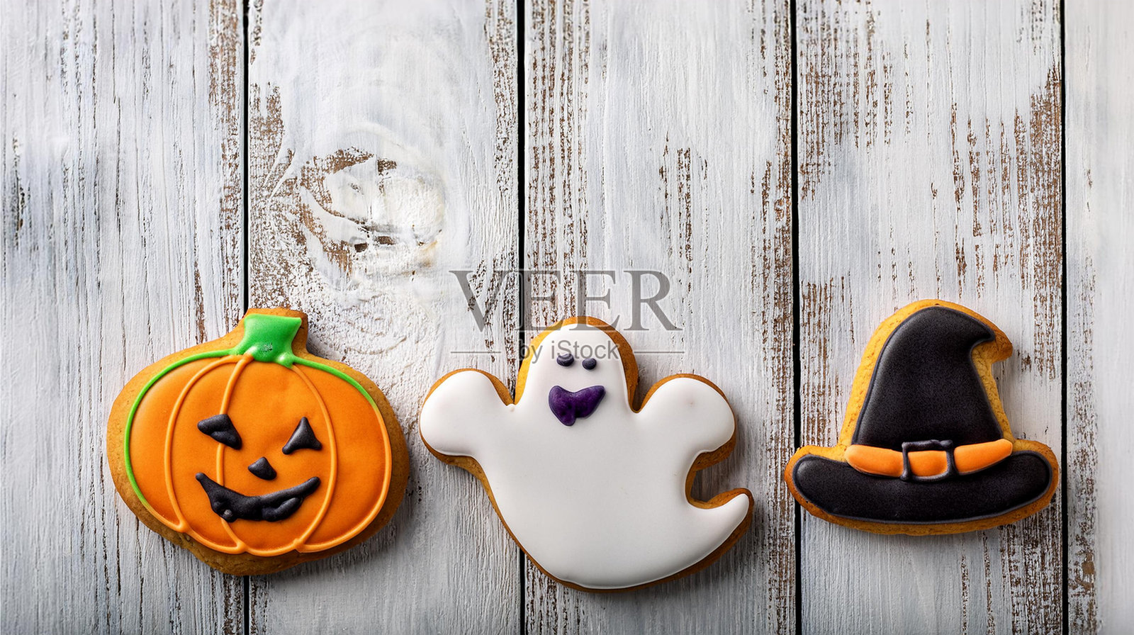 万圣节主题的南瓜、鬼魂和女巫帽冰淇淋饼干,背景为粗犷的木质表面照片摄影图片