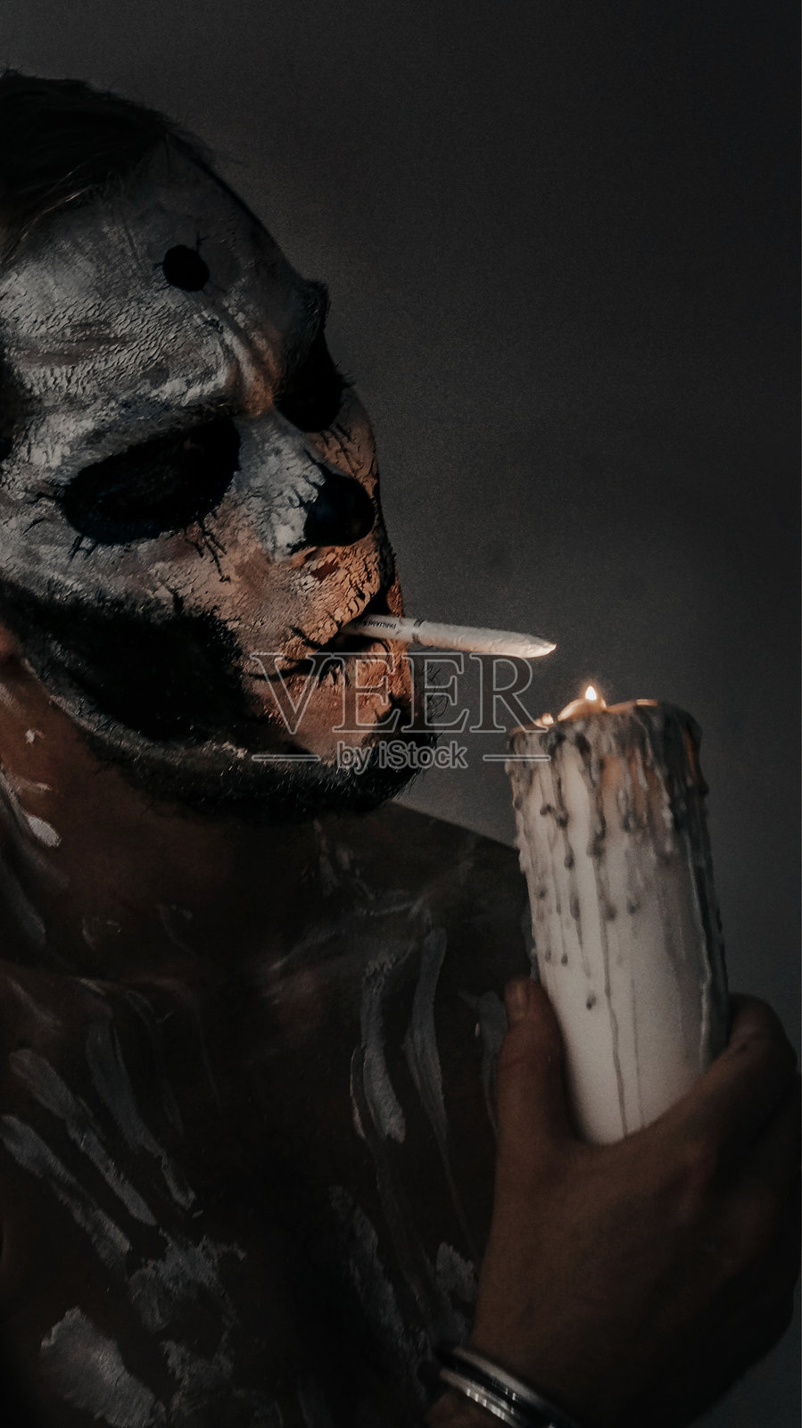 黑暗的照片中,骷髅人用蜡烛点燃香烟的身体艺术照片摄影图片