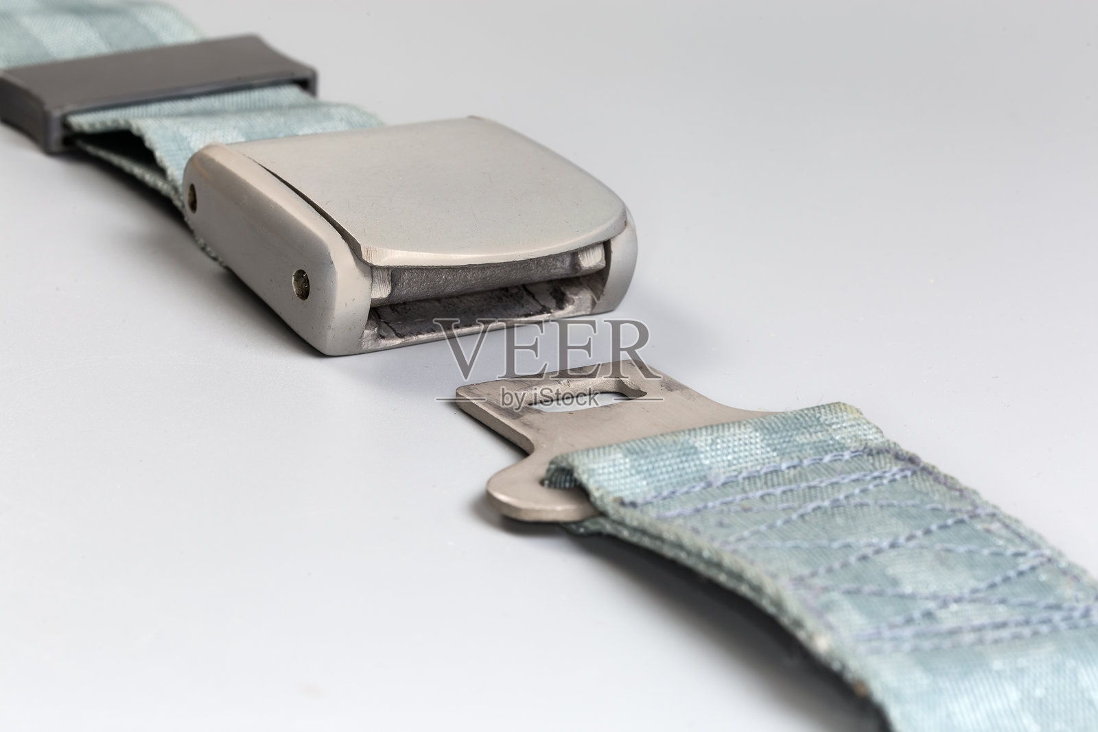 灰色背景上的飞机膝部安全带,扣子未扣上照片摄影图片