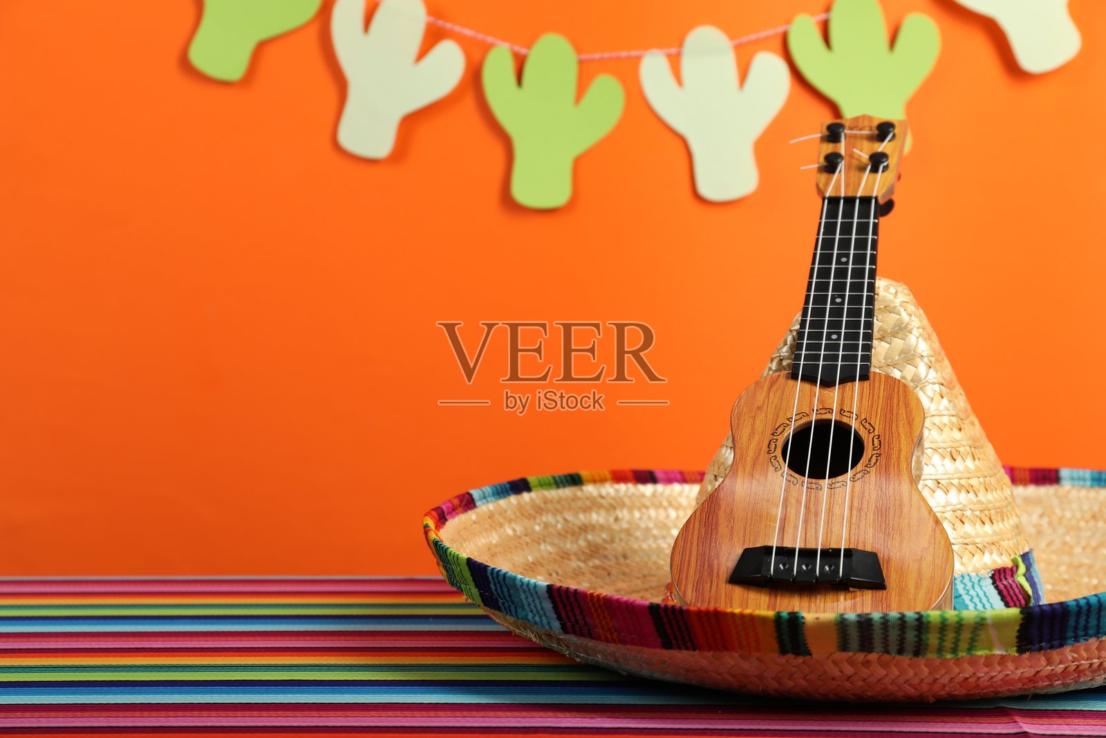 墨西哥草帽和尤克里里放在彩色桌子上,特写。留有文字空间。照片摄影图片