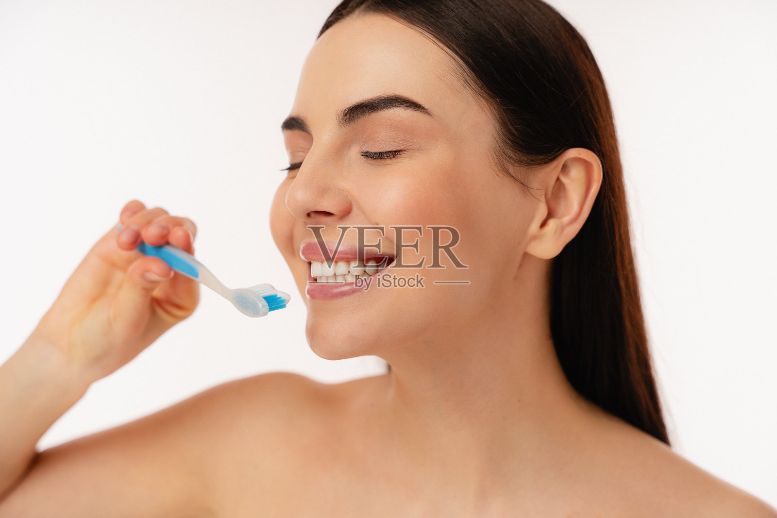 微笑的个人用蓝色牙刷刷牙以保持口腔卫生照片摄影图片