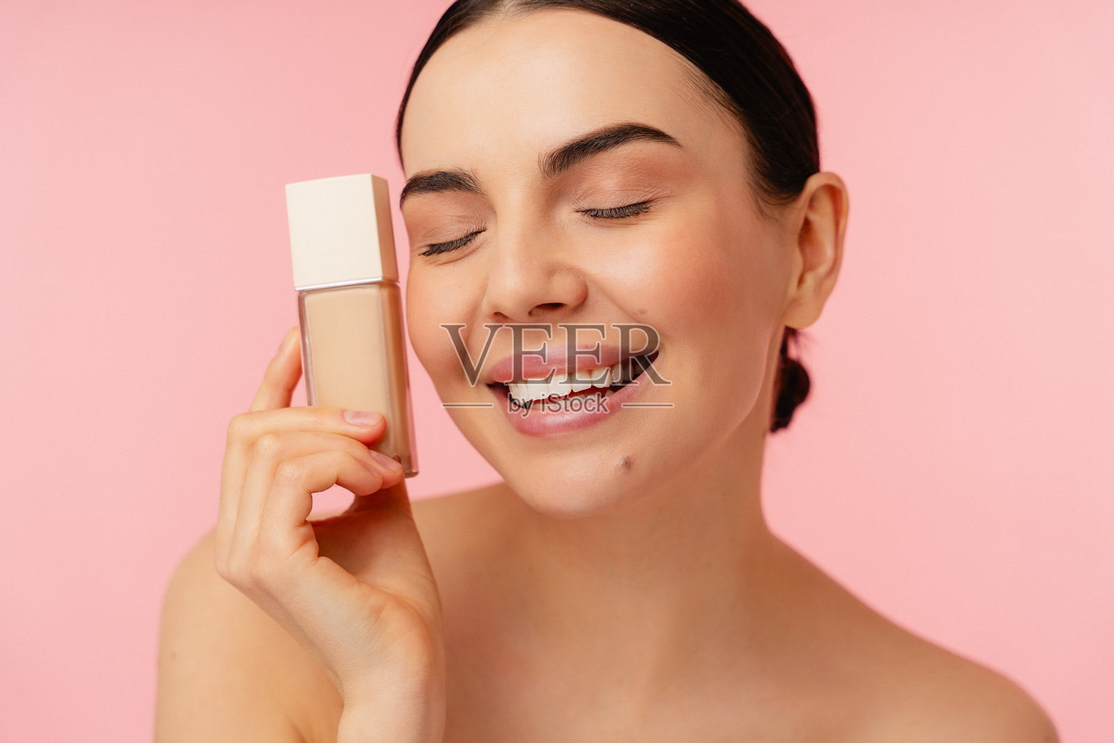 在粉色背景下微笑的光彩照人的个体展示化妆品照片摄影图片