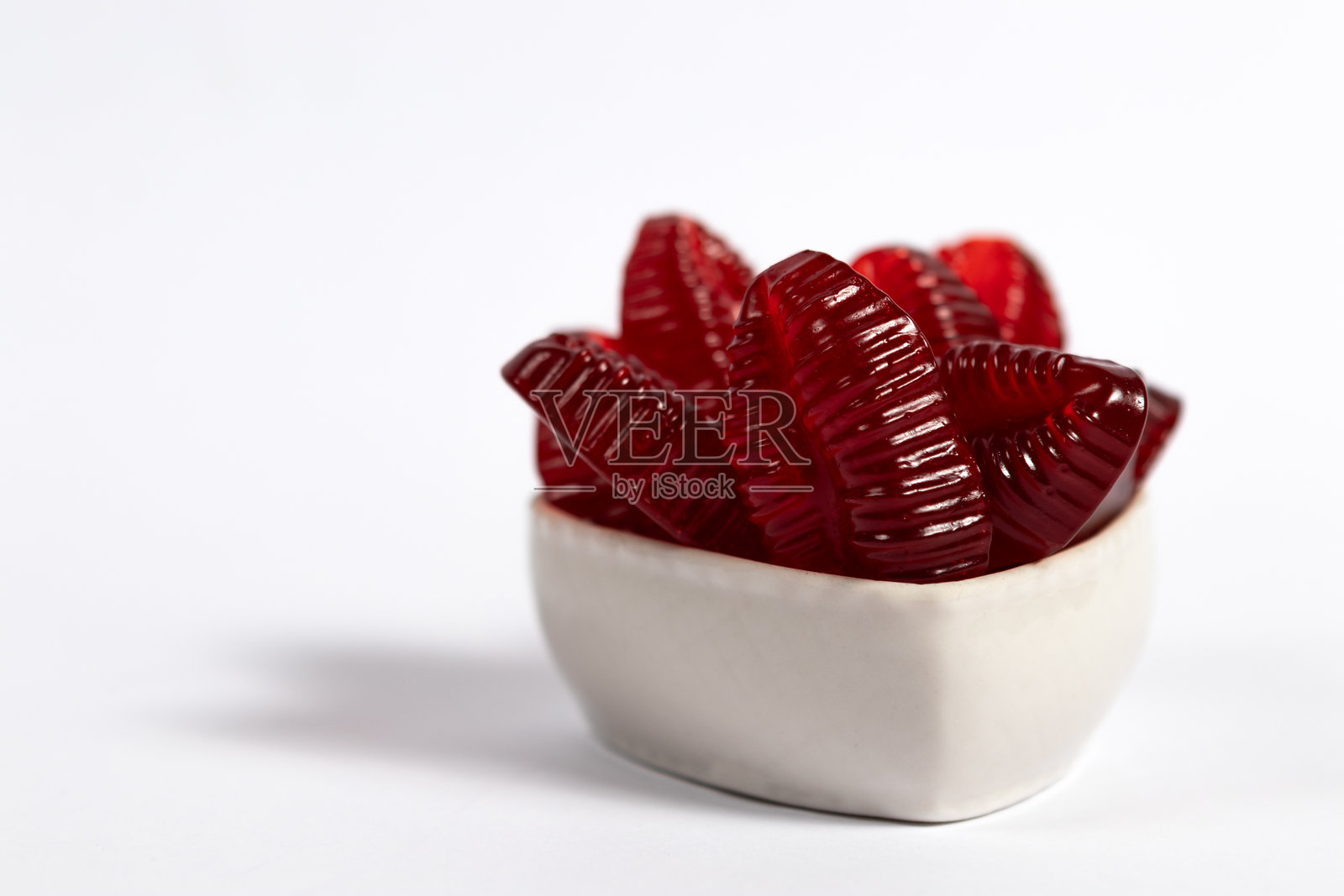 白色背景上的心形碗里装着红色橡皮糖嘴唇照片摄影图片