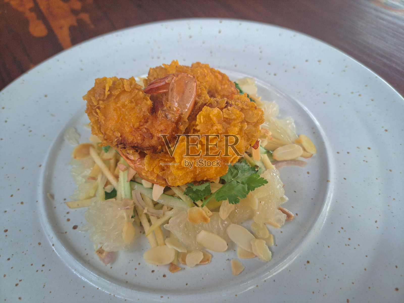 泰式柚子沙拉,配有芒果、黄瓜、柚子和裹粉虾,搭配柚子酱汁。沙拉菜单。照片摄影图片