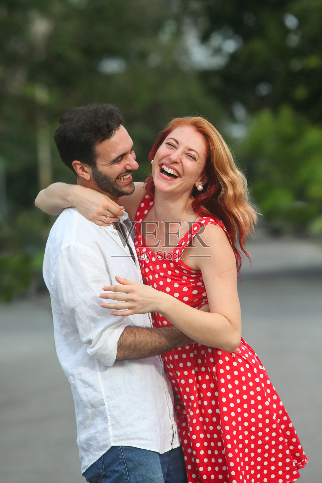 阳光明媚的夏日里,快乐的情侣在户外相拥而坐。照片摄影图片