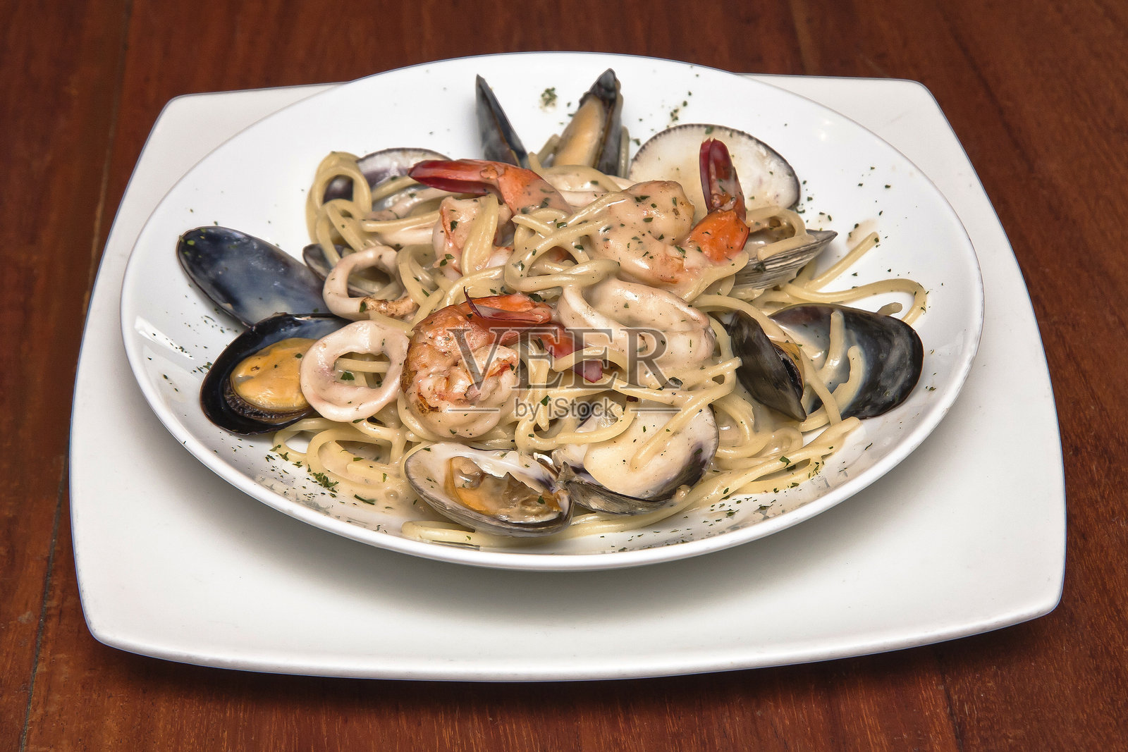 美味的海鲜蛤蜊意大利面盛在白色盘子里,放在木桌上照片摄影图片