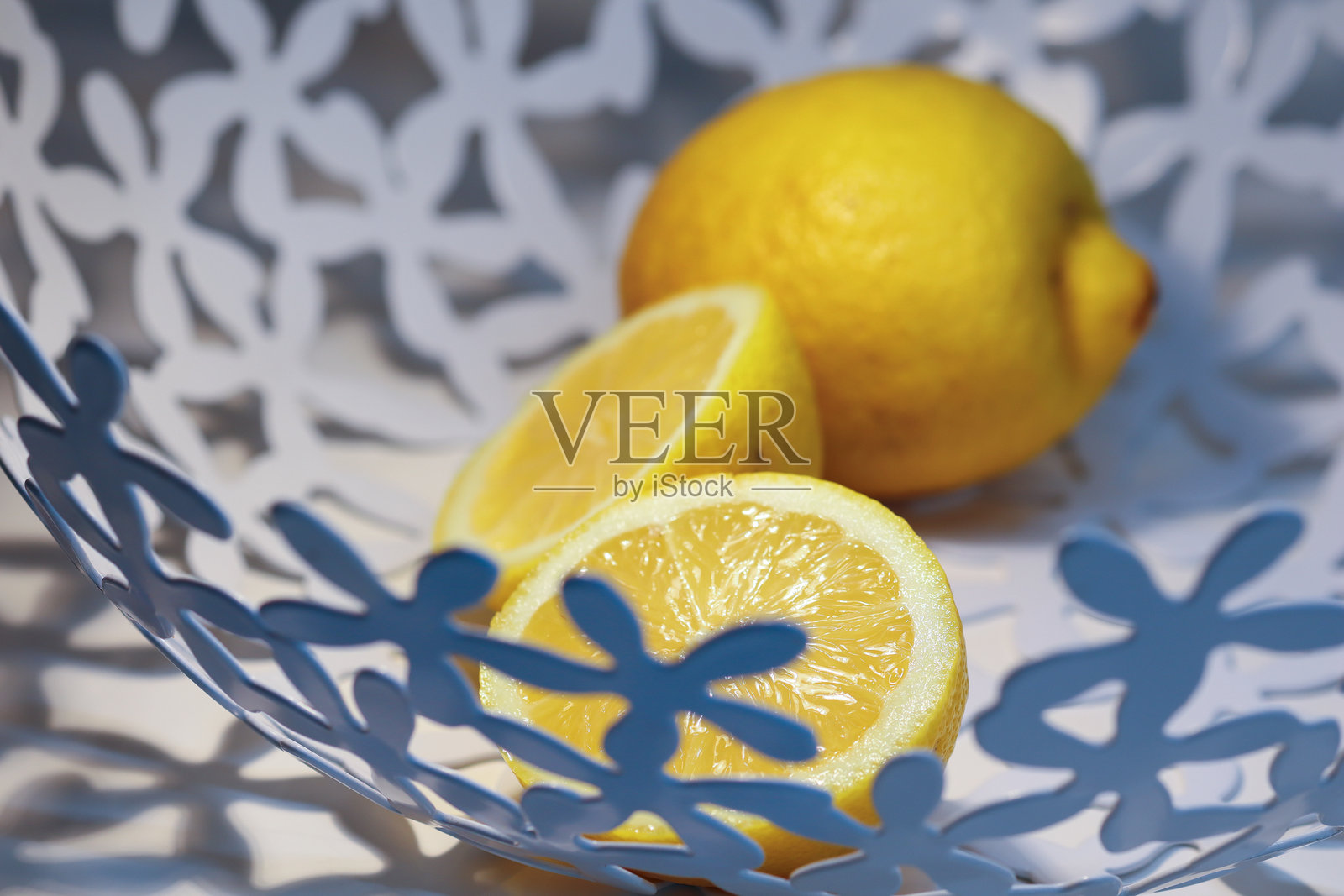 一个新鲜的柠檬和两片多汁的柠檬片放在一个装饰图案的盘子上。照片摄影图片