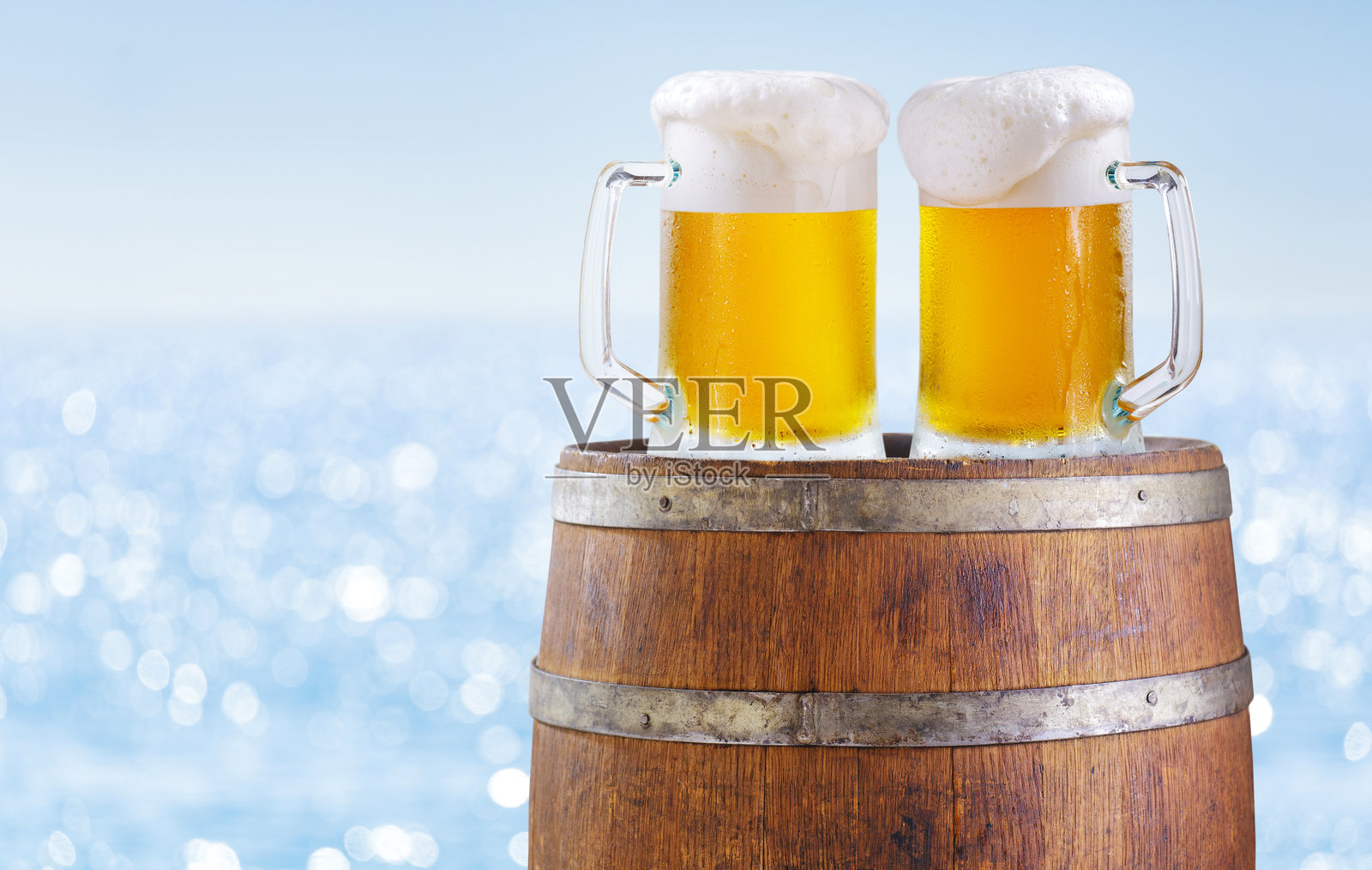 海景背景下的木桶上的啤酒杯照片摄影图片