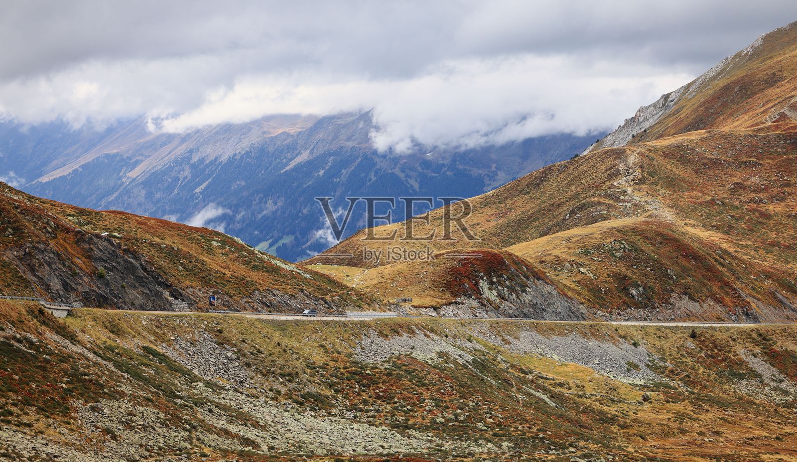 蜿蜒的山路穿过秋天的山丘。照片摄影图片