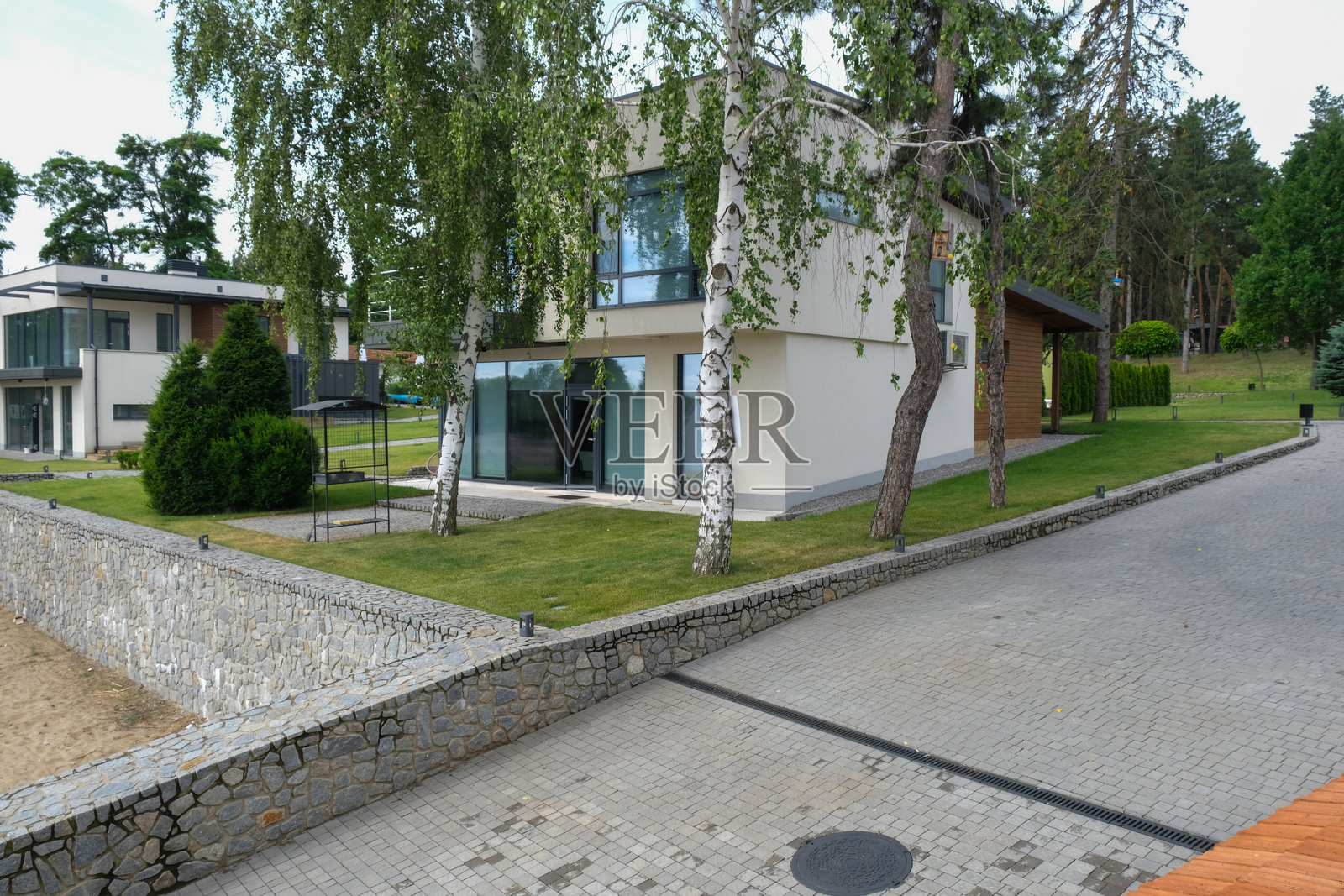 现代乡村小屋,周围有烧烤区和树木照片摄影图片