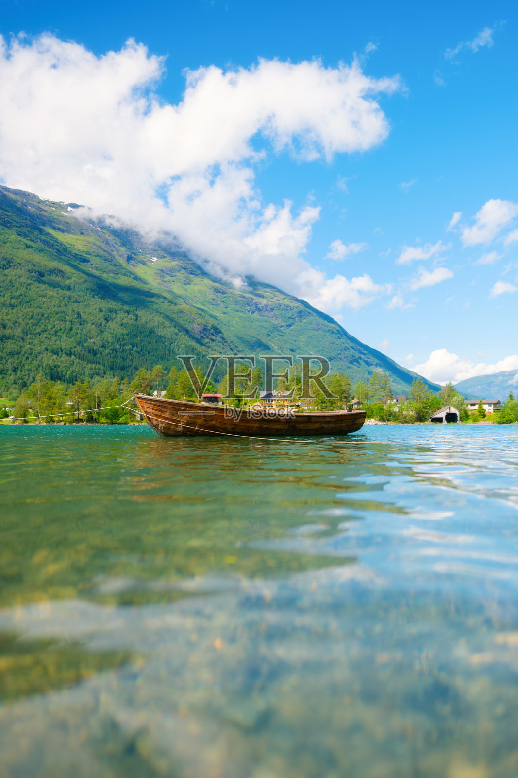 挪威峡湾的山湖中的木船。峡湾中的自然景观。高耸的山脉和水面上的倒影。夏季挪威的度假与旅行。照片摄影图片