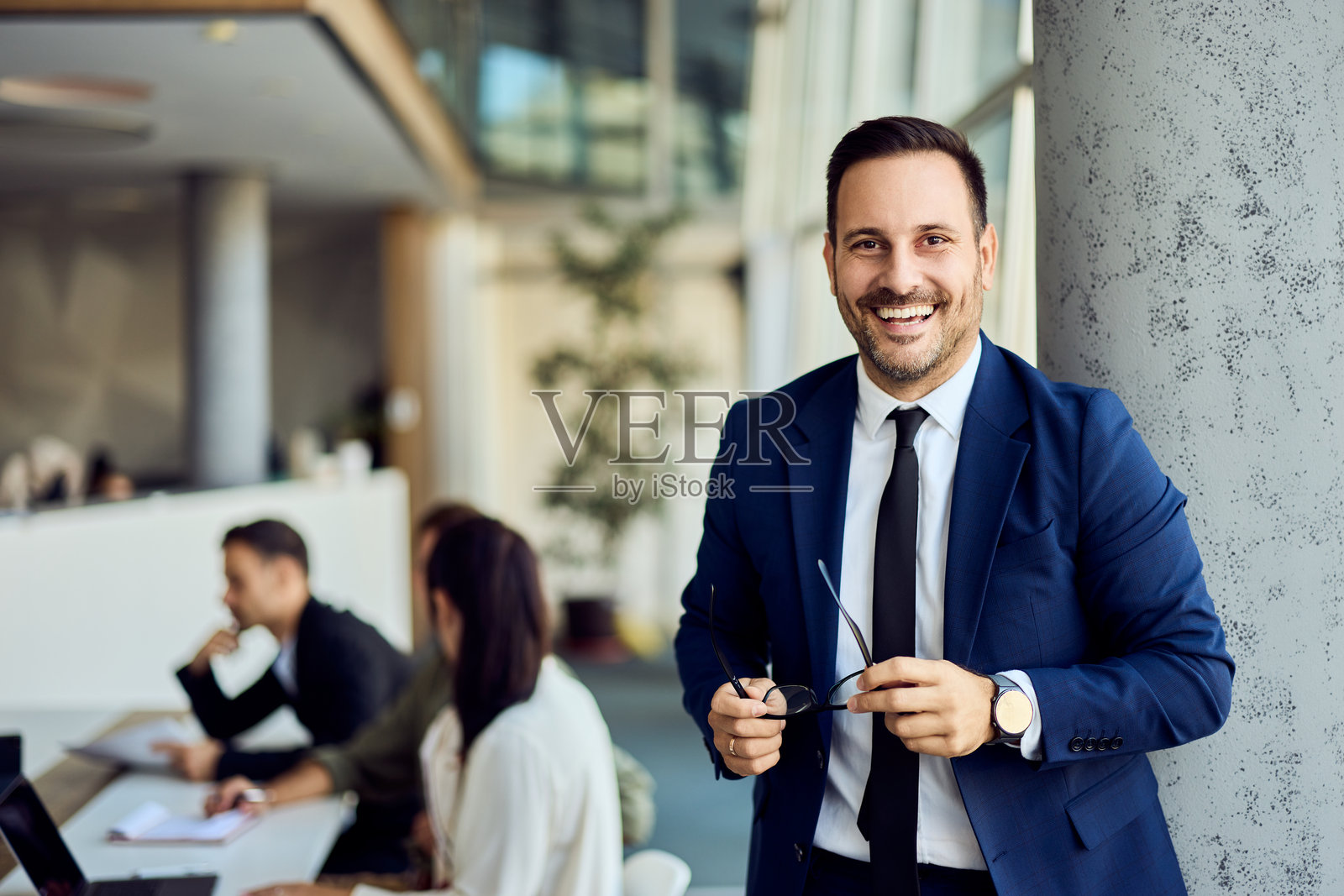 微笑的商人在办公室环境中,背景中同事们正在合作照片摄影图片