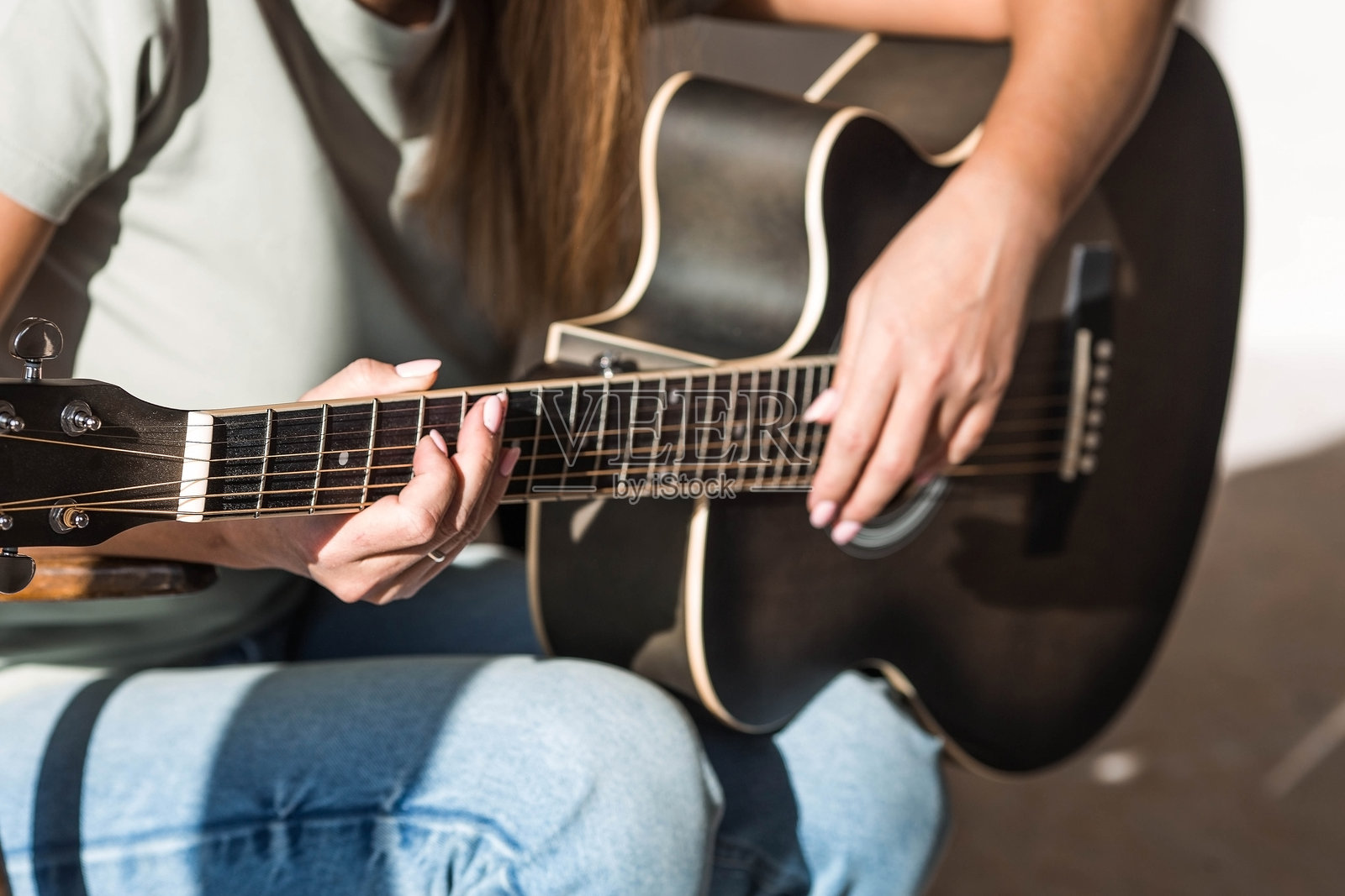 一位才华横溢的年轻女音乐家独自坐着,弹奏吉他创作歌曲。她在乐器上演奏着悠扬的旋律。音乐与爱好。照片摄影图片
