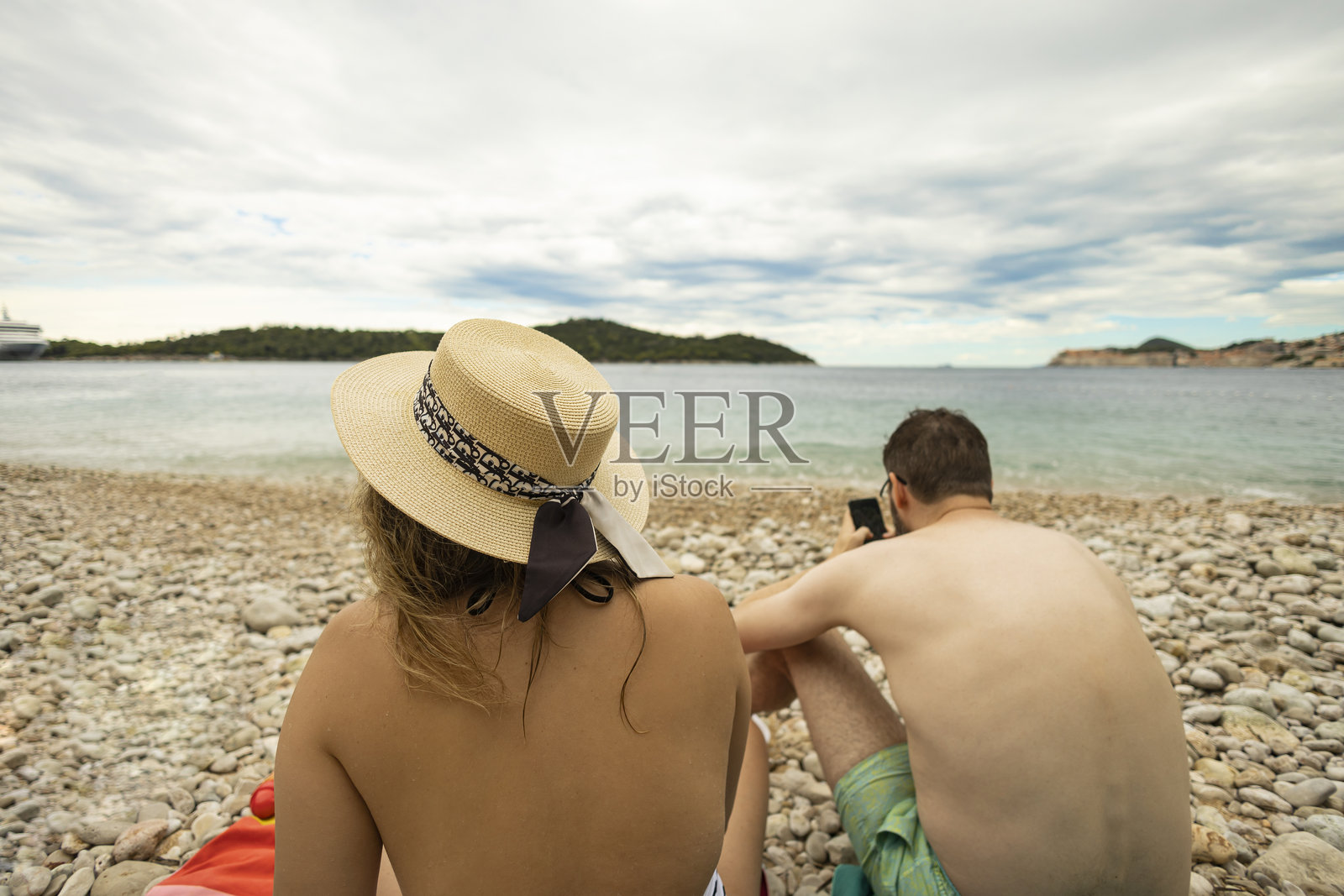 夫妻坐在海滩上交谈,享受异国情调的野生海滩。照片摄影图片