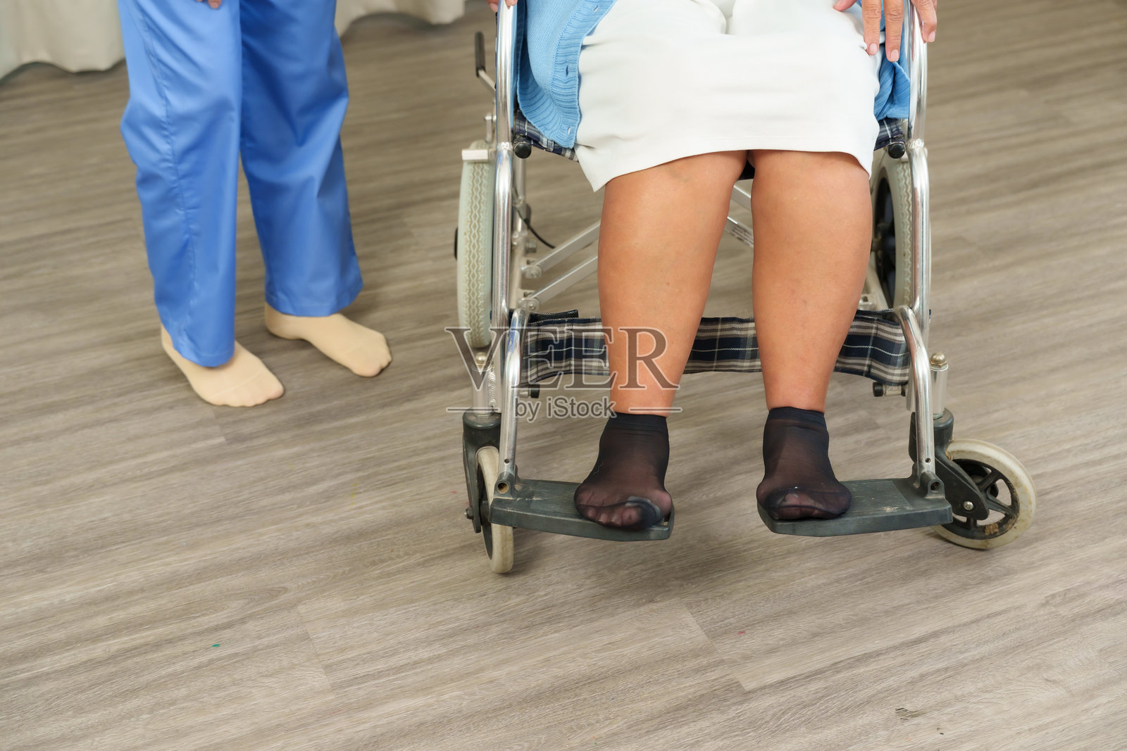 物理治疗师在病人康复后照顾一位老年人。特写镜头显示坐在轮椅上的老年女性,旁边有护士站立。家庭医疗服务提供支持。照片摄影图片