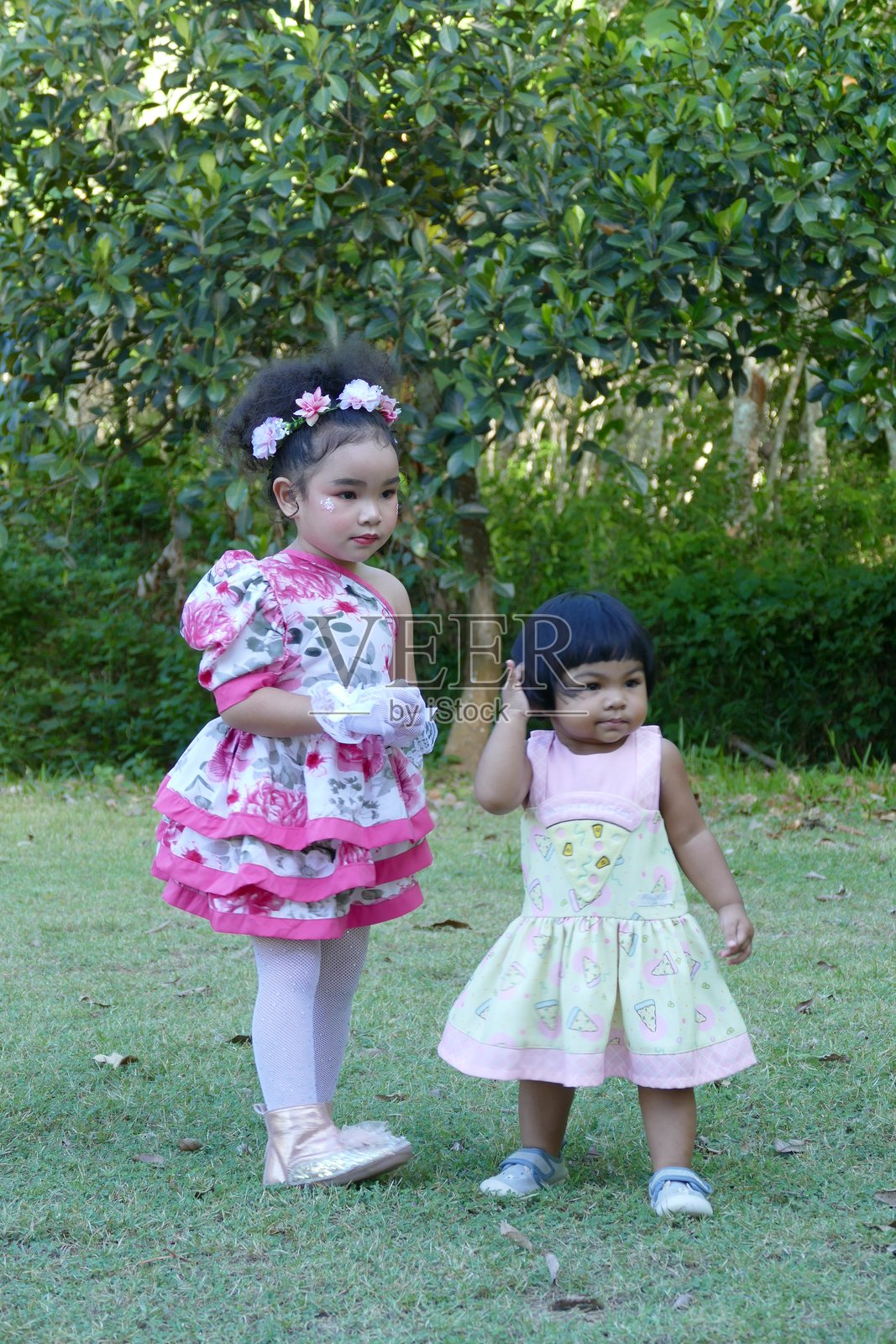 两个穿着粉色裙子的小女孩在花园里快乐地合影照片摄影图片