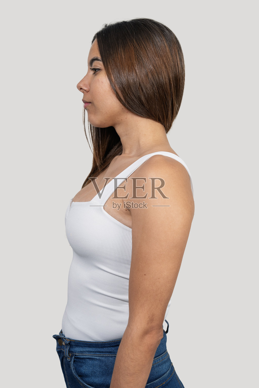 年轻女性穿着白色上衣和牛仔裤的工作室拍摄照照片摄影图片