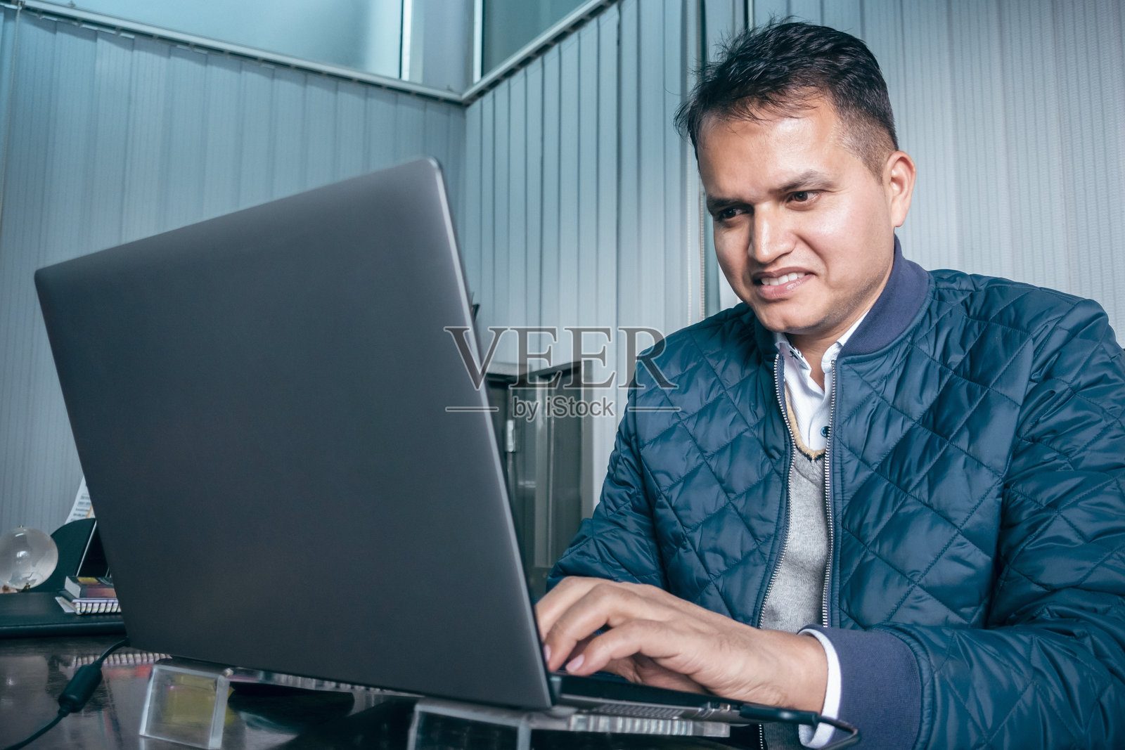 商人在他的办公室小隔间里使用笔记本电脑工作。照片摄影图片