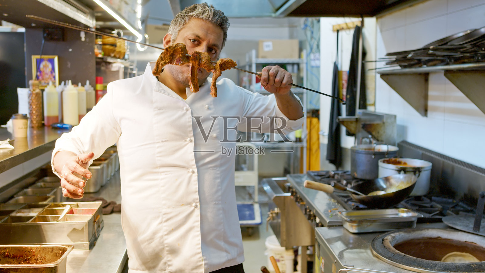 主厨在悉尼的印度餐厅厨房展示装有腌制肉类的长串烤肉。照片摄影图片