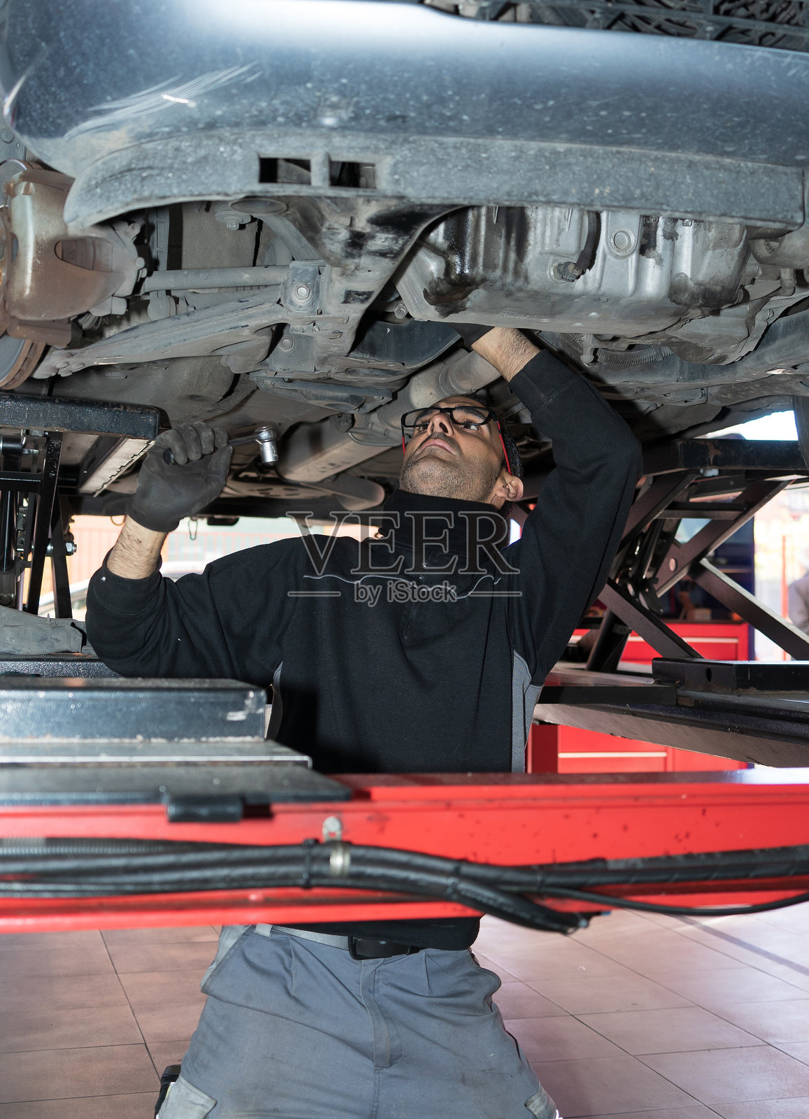 技师在升降机上检查汽车底盘照片摄影图片