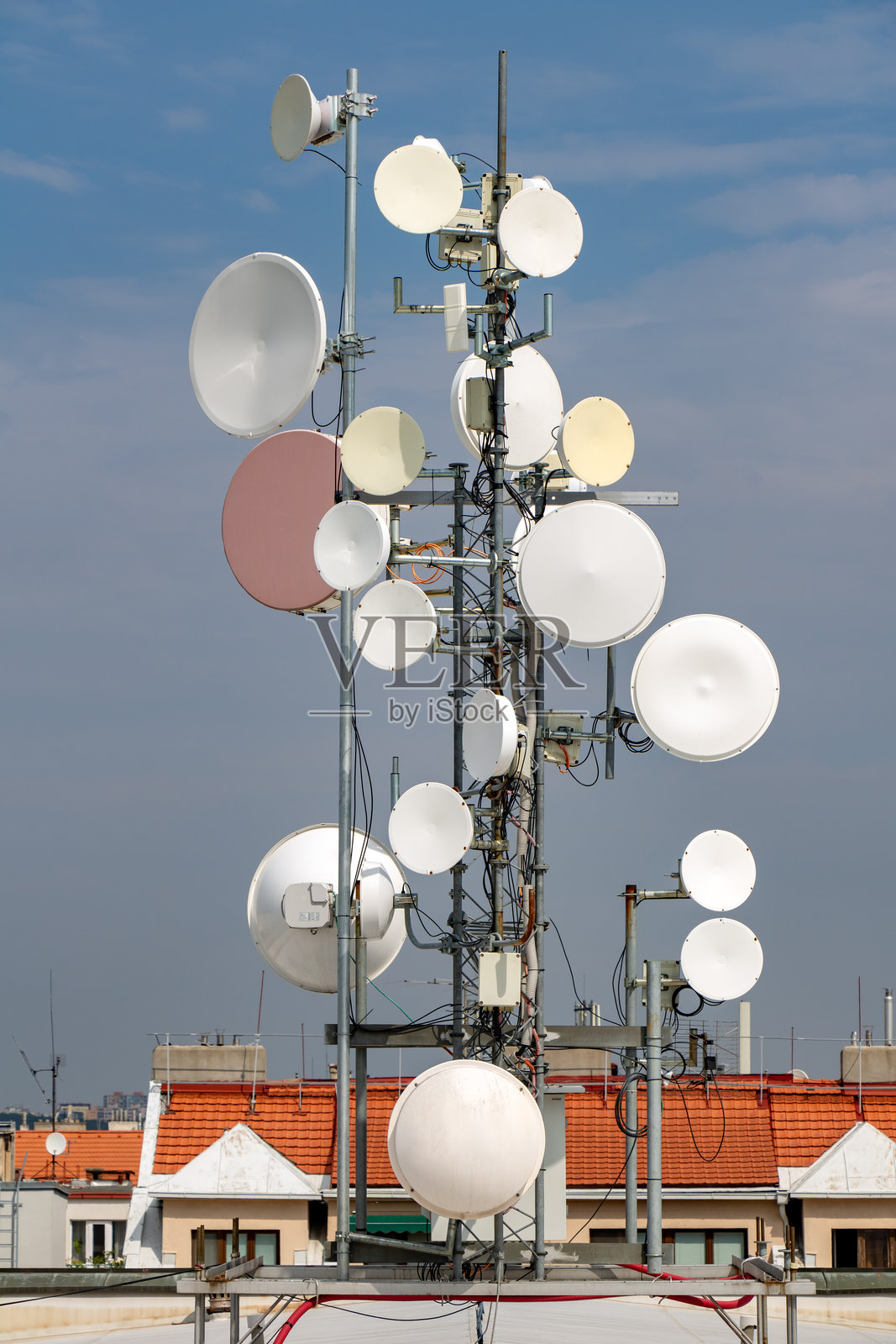 蓝色背景下,屋顶上的微波链路通信塔。照片摄影图片