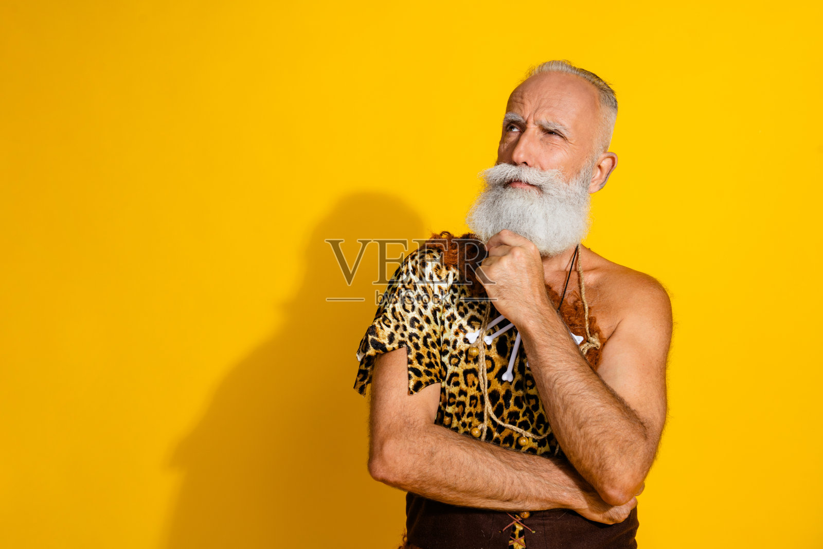 穿着豹纹衣服的古老洞穴人站在黄色背景前,面无表情,显得空洞。照片摄影图片