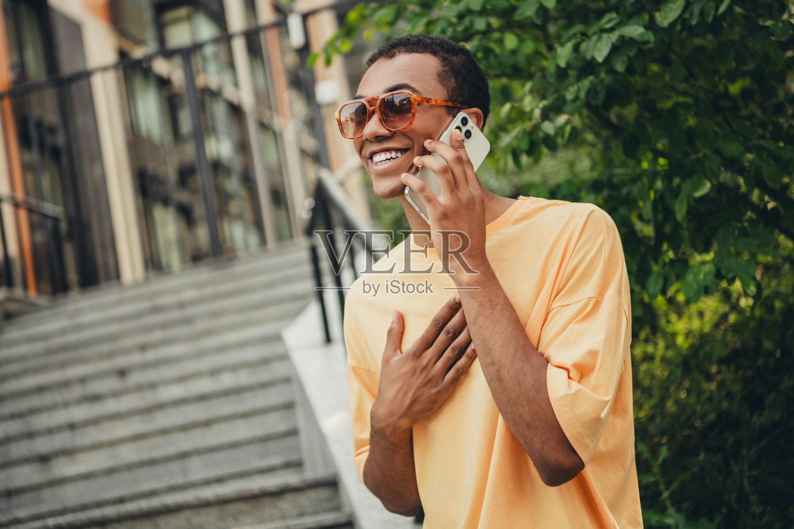 年轻的非裔美国男子在阳光明媚的城市户外享受电话通话照片摄影图片