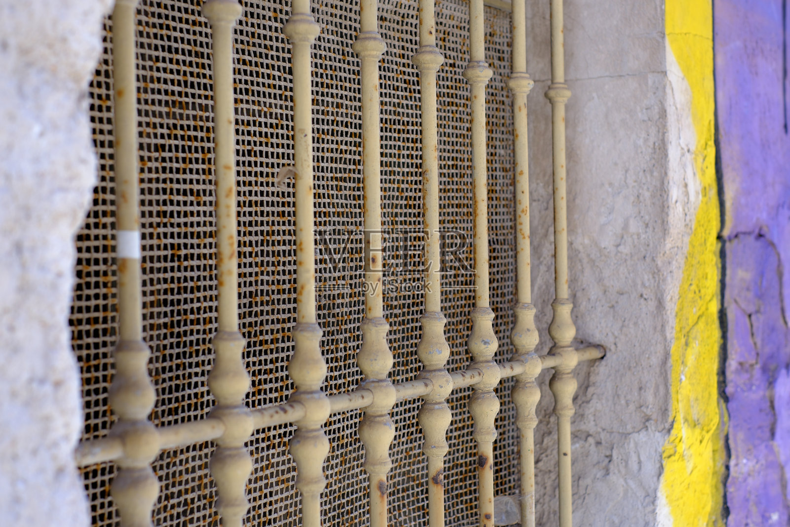 陈旧的金属窗格与风化的石墙,点缀着鲜艳的黄色。照片摄影图片