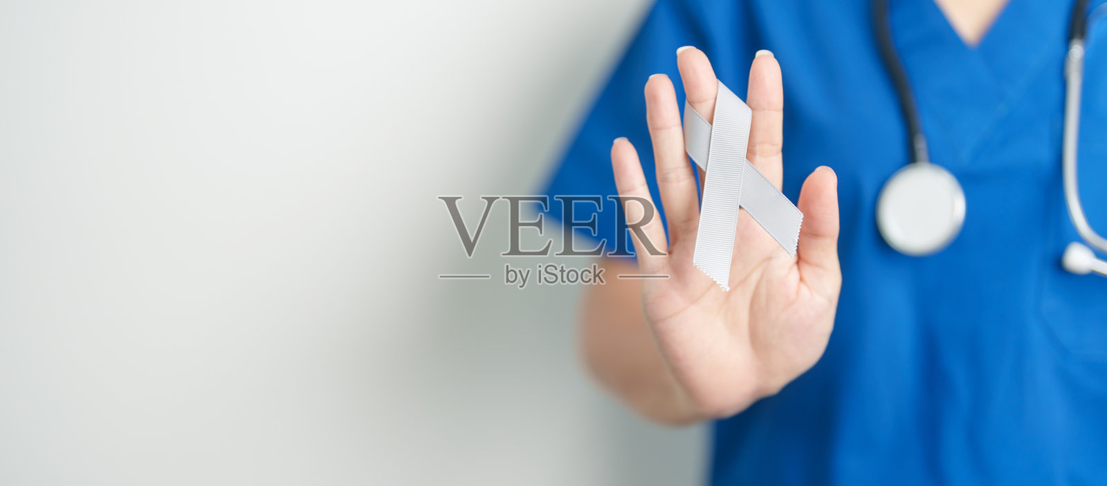 脑癌意识月,医生手持灰色丝带以支持生命。医疗保健与世界癌症日概念。照片摄影图片