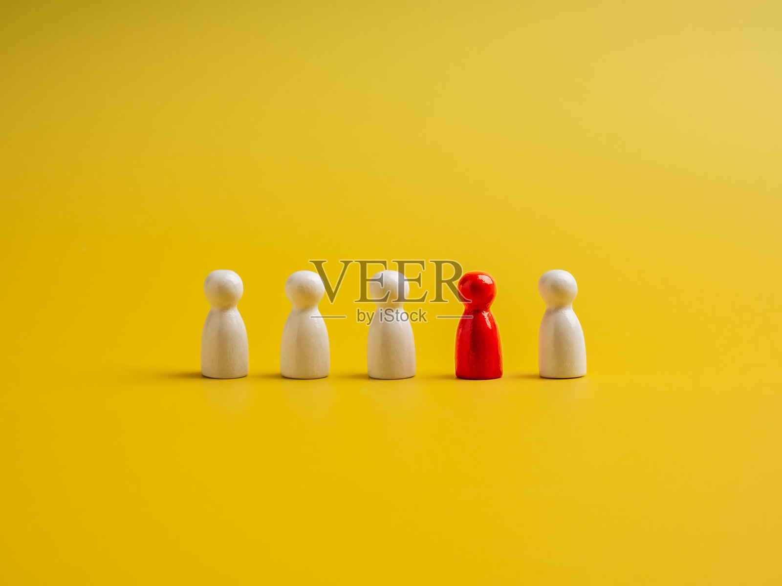 红色的木偶在人群中脱颖而出,周围是白色的木偶,背景为黄色。突出于人群,领导力,独特,影响力,人才,差异概念。照片摄影图片