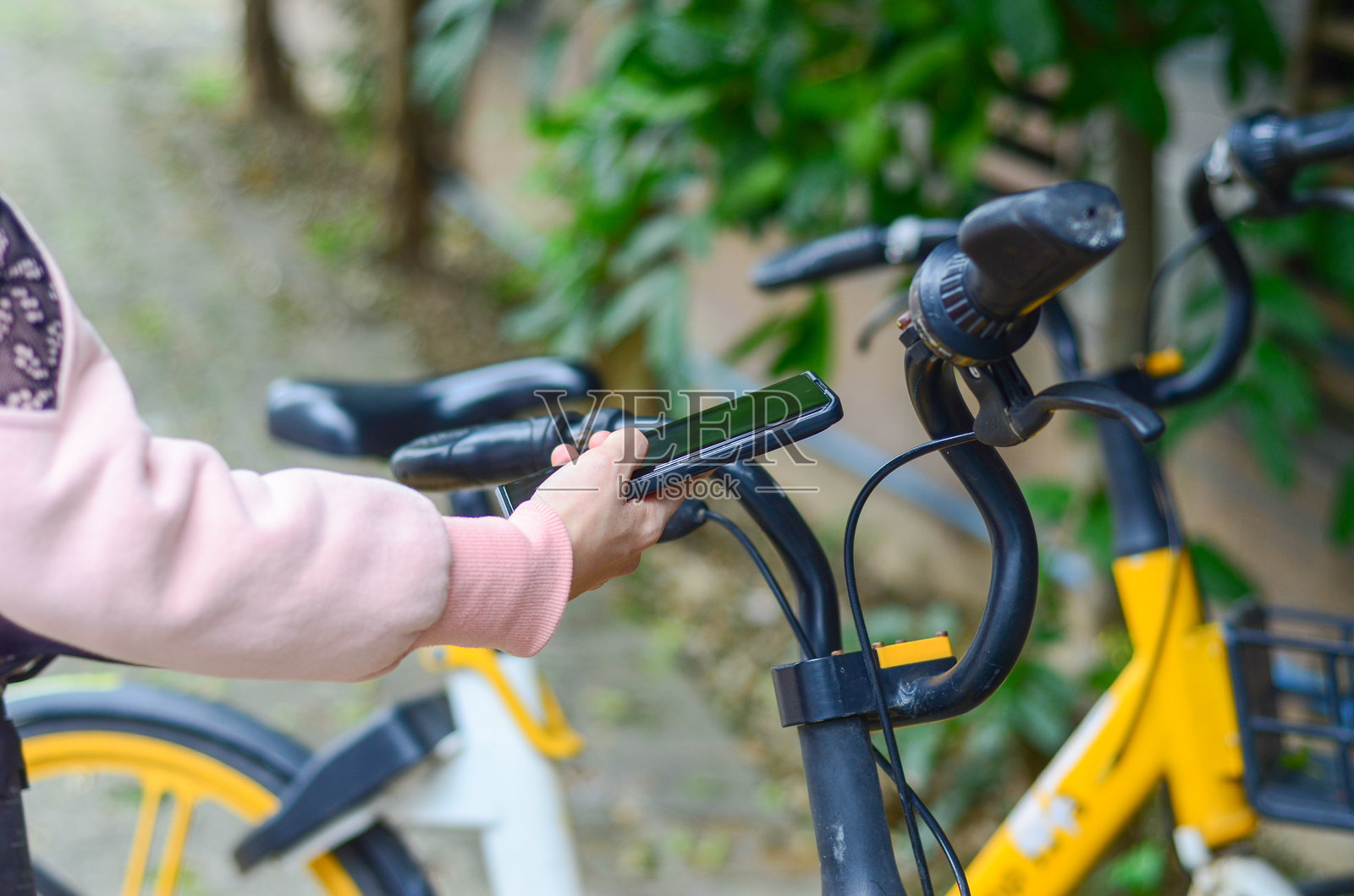 通勤者使用智能手机扫描共享单车上的二维码以解锁。照片摄影图片