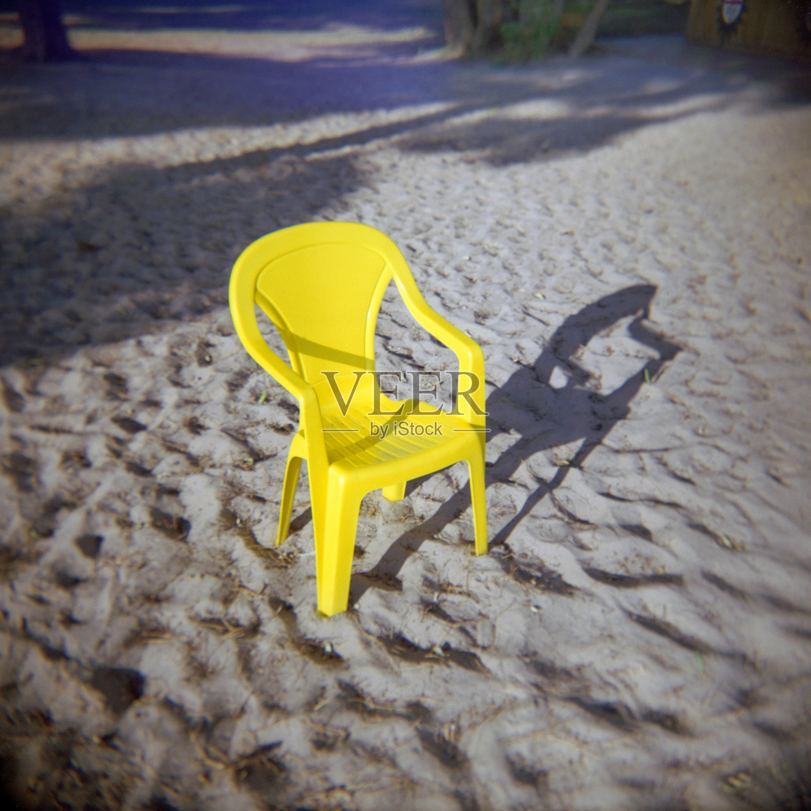 一把孤独的黄色椅子,背景是沙滩,采用胶卷拍摄和复古风格。照片摄影图片