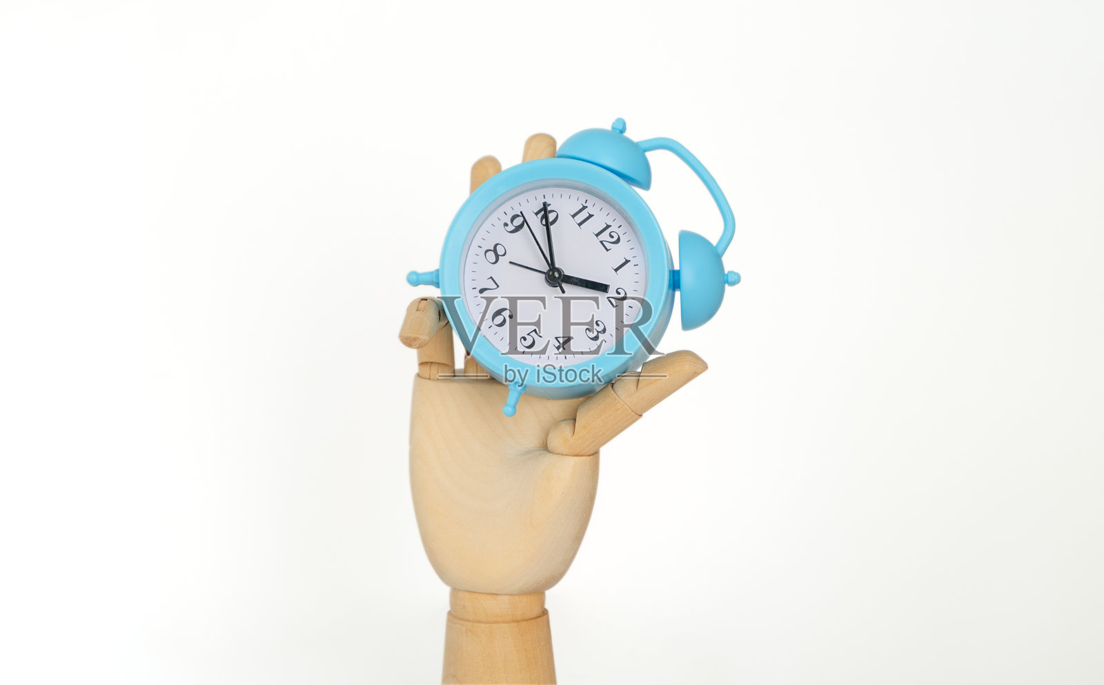一只手握着一个蓝色的闹钟,时间是11:30。照片摄影图片
