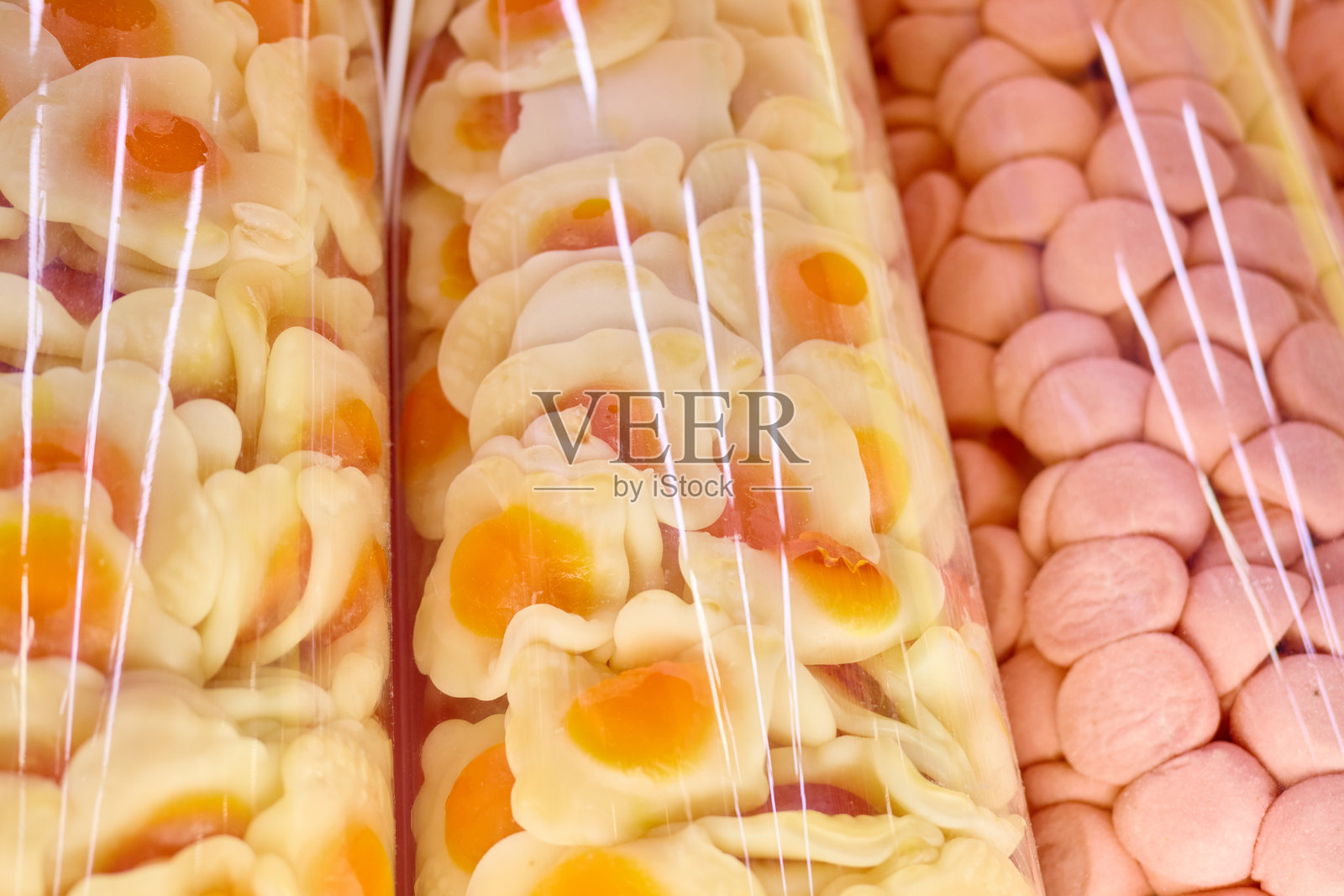 五颜六色的糖果整齐地摆放在糖果店的透明容器中。这些欢快的糖果组合具有独特的形状和鲜艳的色彩,吸引着顾客。照片摄影图片