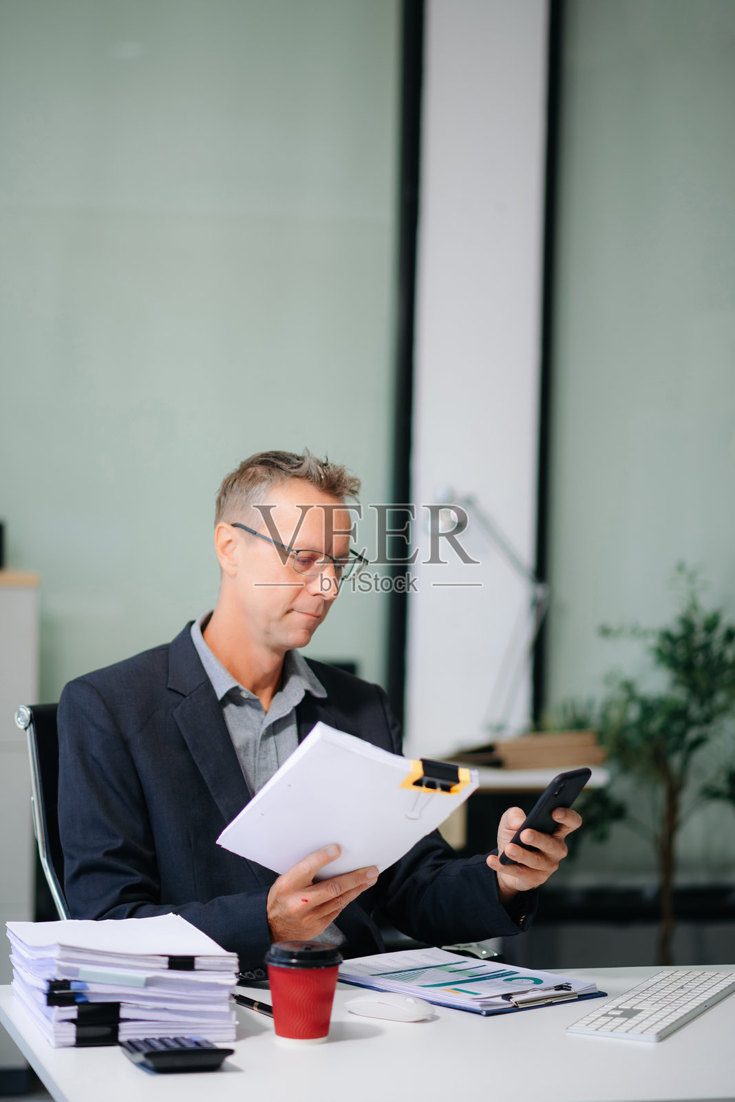 自信的商人在办公室桌子上使用平板电脑和笔记本电脑进行财务分析。非常适合商业用途。照片摄影图片